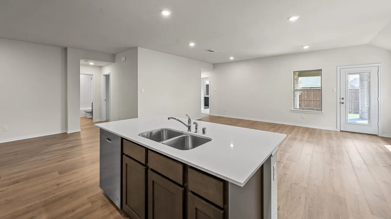 Kitchen island with dual stainless steel sink, white countertop, and dark wood-finish cabinetry