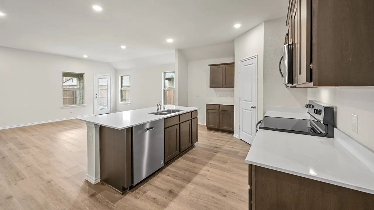 Kitchen featuring wood-finish flooring, recessed lighting, white countertops, stainless steel appliances, and dark wood cabinetry