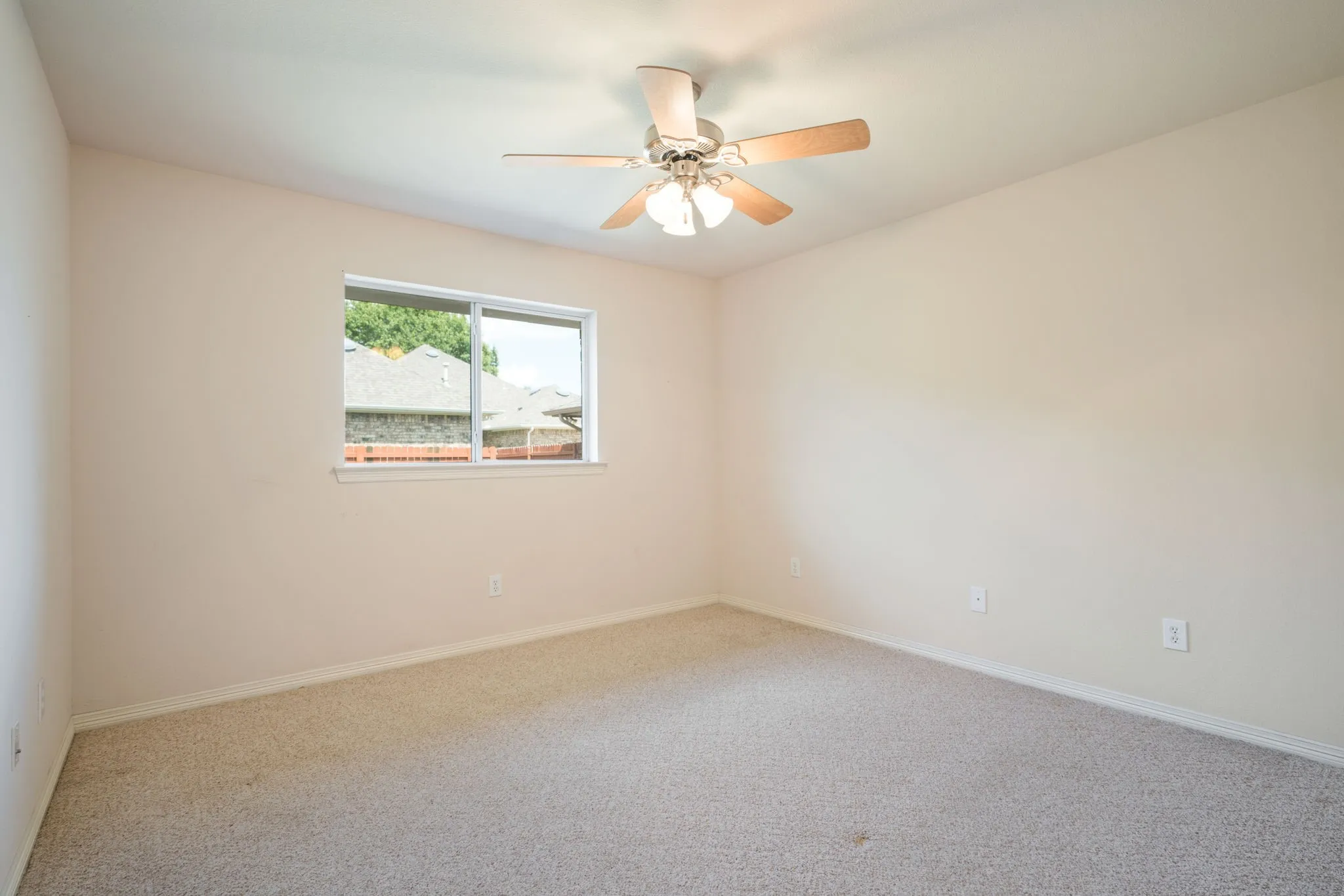 Recessed window, ceiling fan with integrated lighting, and neutral tone carpeting