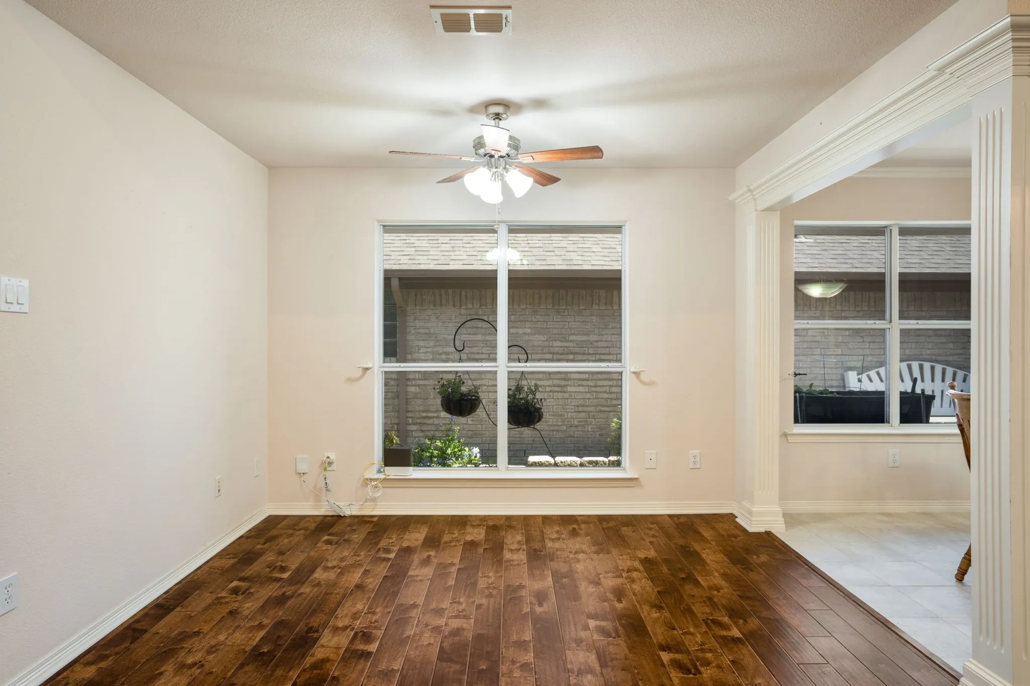 Wood-finish flooring, ceiling fan with integrated lighting, and white trim throughout