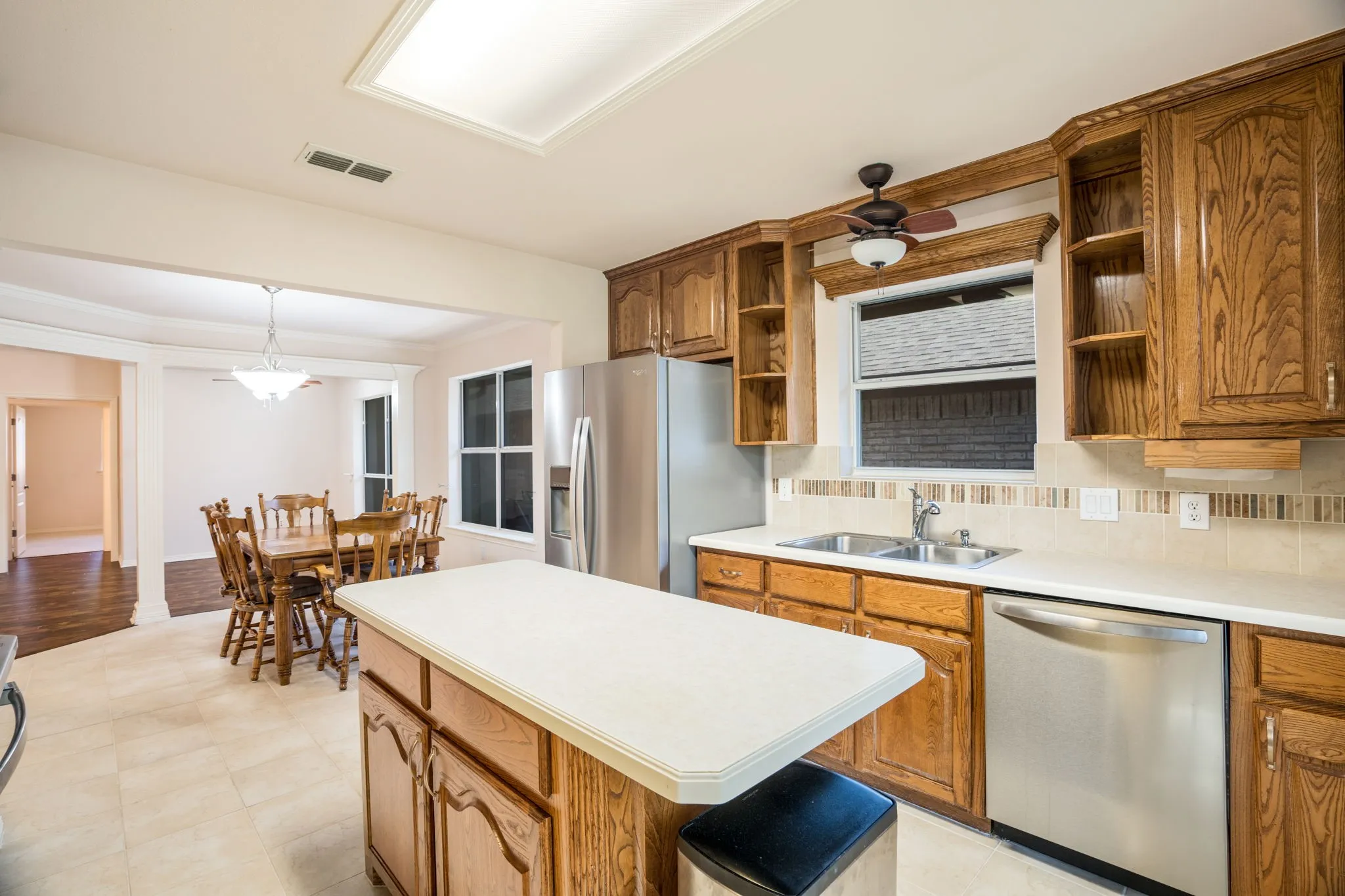 Kitchen with medium wood-tone cabinetry, stainless steel appliances, and a central island with a solid surface countertop