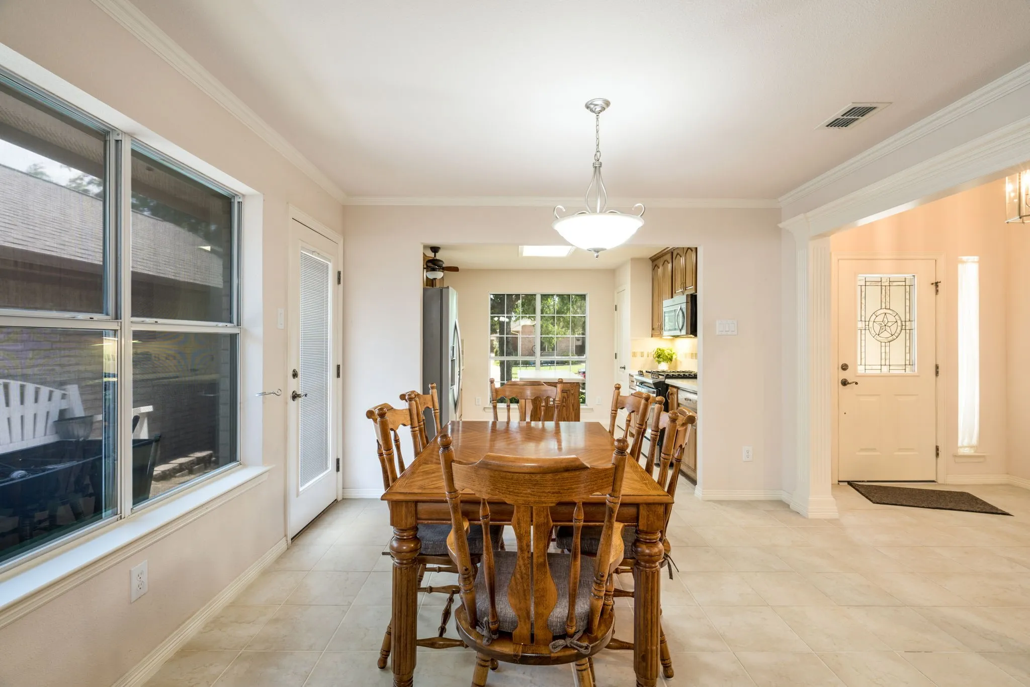 Tile flooring, decorative glass entry door, crown molding, double-pane windows, and a pendant light fixture