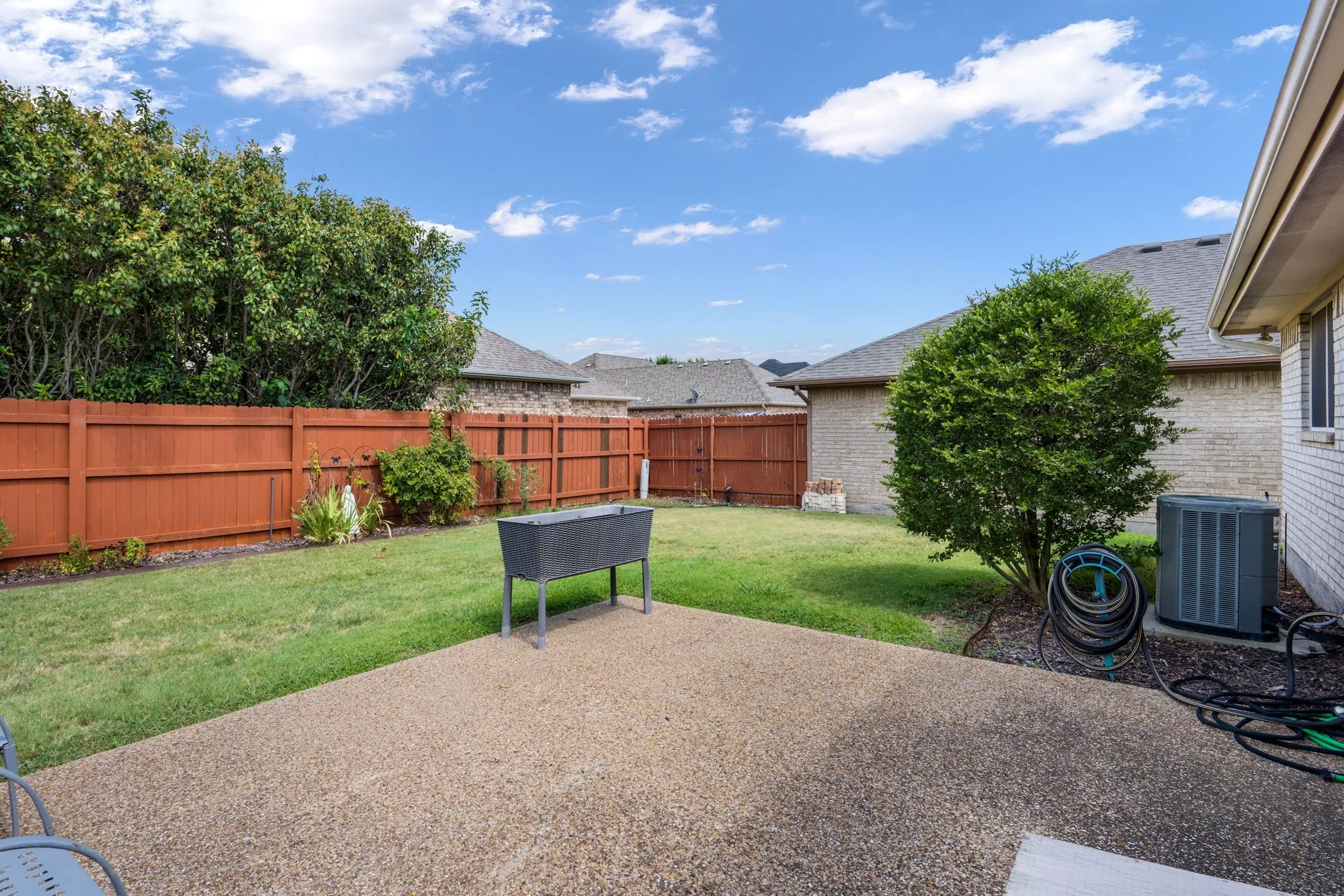 Expansive backyard featuring a concrete patio, a manicured lawn, and a wood fence