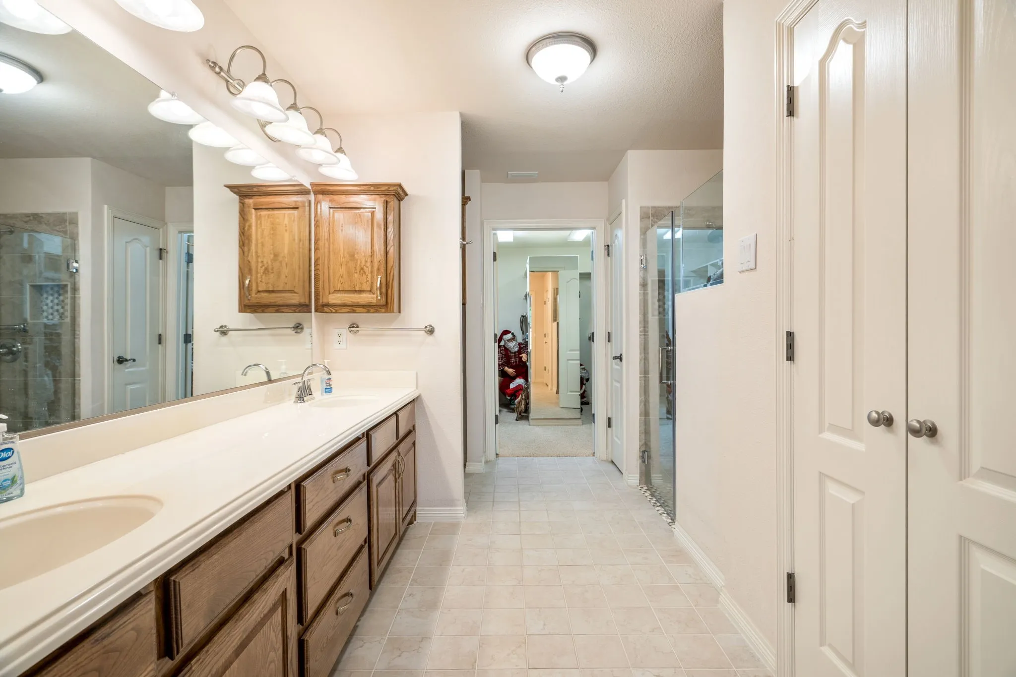 Long vanity with integrated sink, wood cabinetry, and overhead lighting