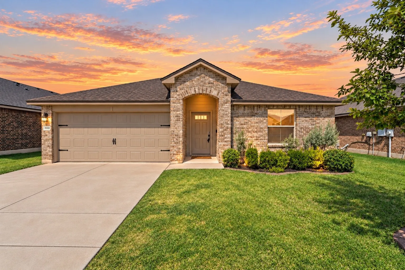 Brick exterior with an arched entry, attached garage, and a concrete driveway