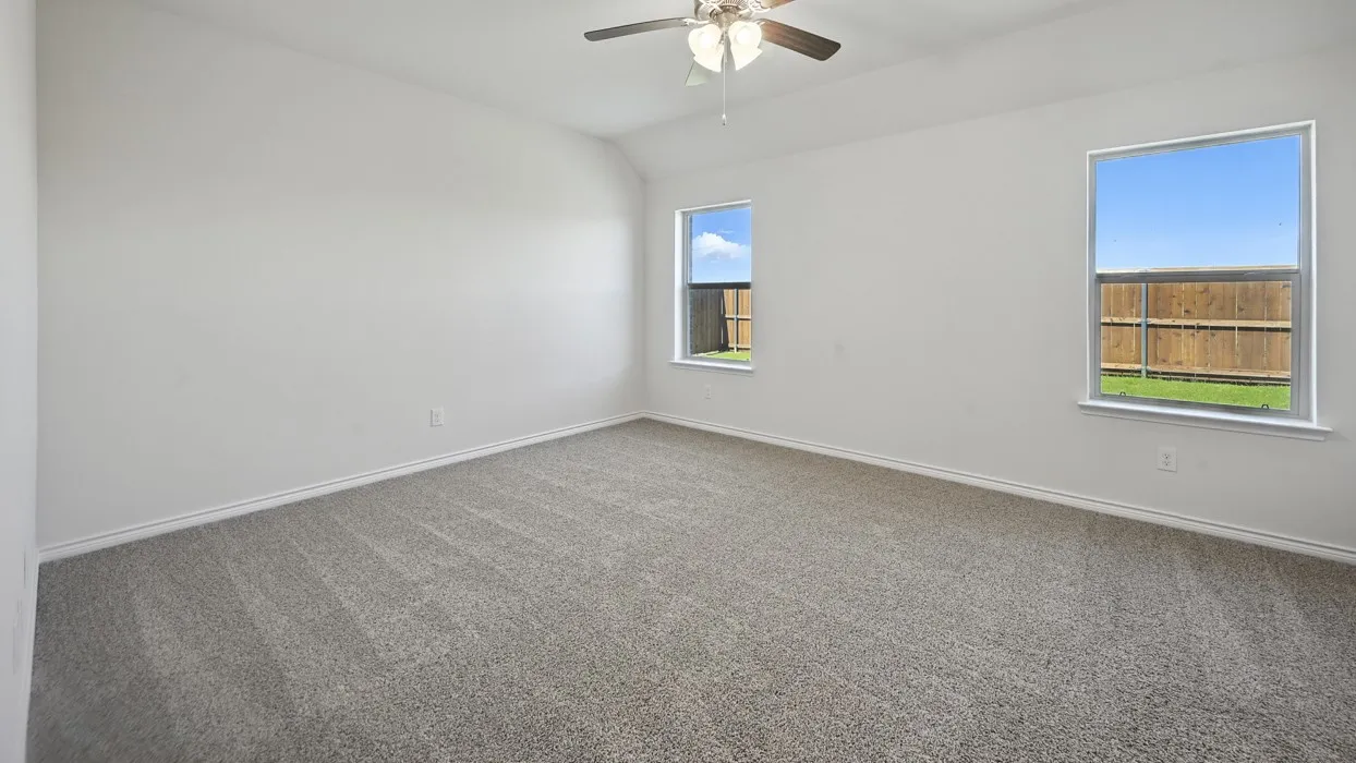 Carpeted room with a ceiling fan, two windows, and a wood privacy fence