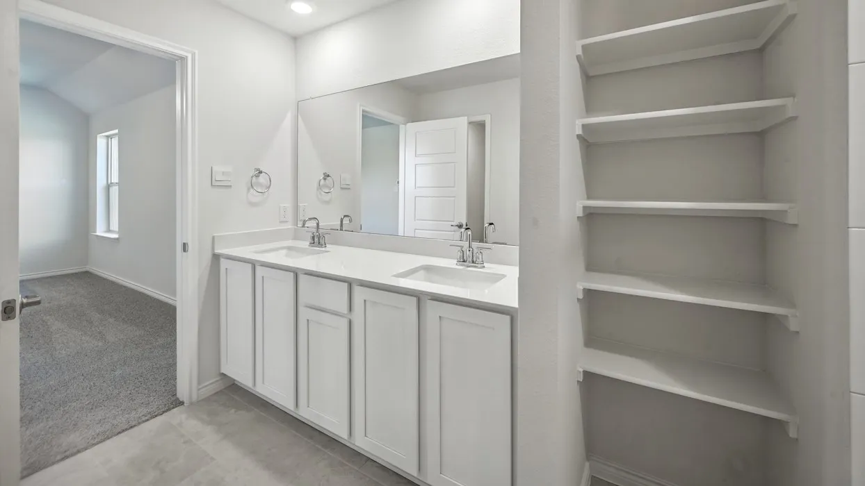 Dual vanity with white cabinetry and integrated sinks, a large wall-mounted mirror, and recessed lighting