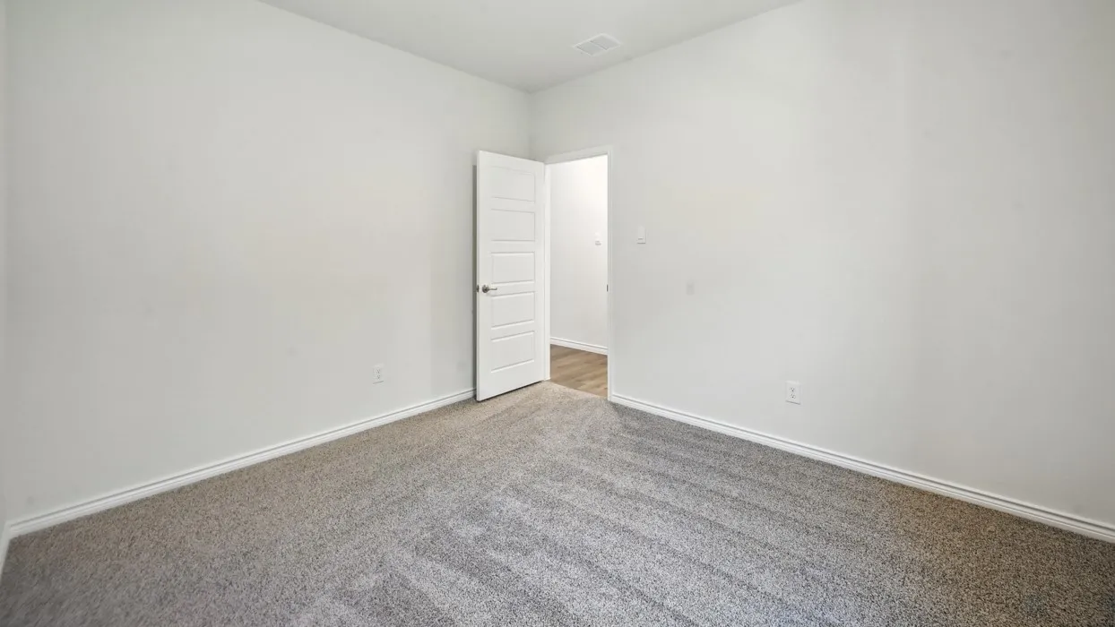 Neutral tone wall paint, light gray carpet flooring, and a white paneled interior door
