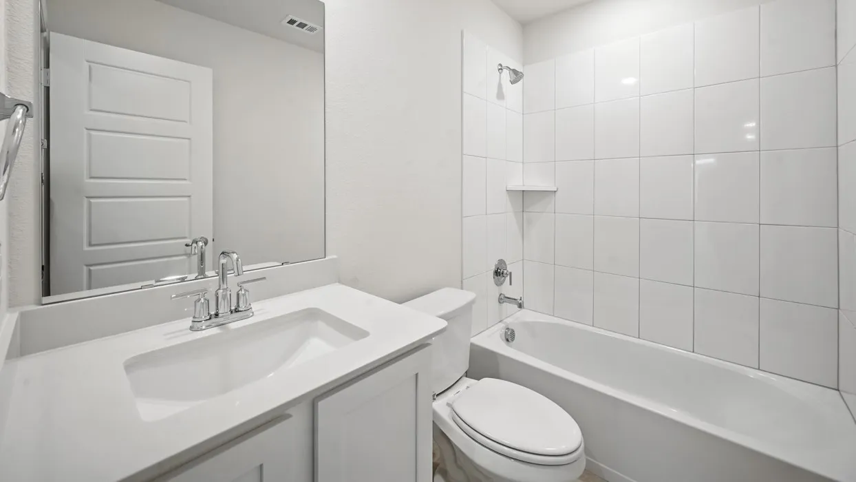Bathroom featuring a single vanity, a polished chrome faucet, a rectangular undermount sink, a large mirror, and a tiled tub/shower combination