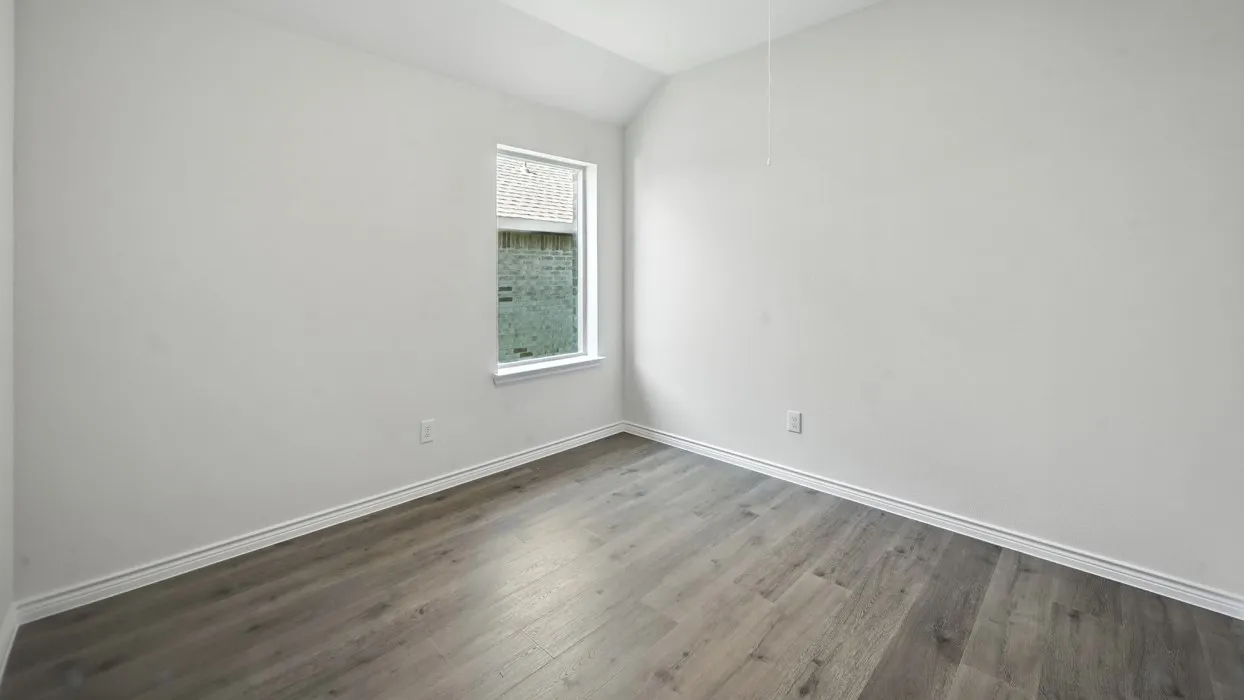 Vaulted ceiling, wood-finish flooring, white walls, and a single window