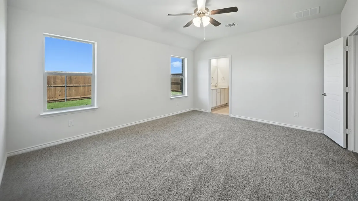 Spacious room featuring vaulted ceilings, carpet flooring, and two windows