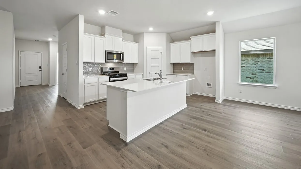 Open-concept kitchen featuring an island, white cabinetry, integrated stainless-steel microwave, and wood-finish flooring