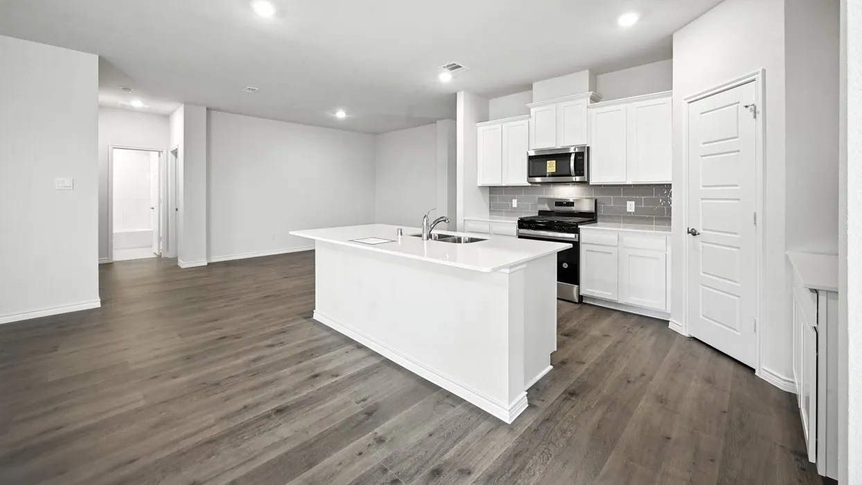 Open-concept kitchen and living area featuring wood-finish flooring, recessed lighting, and a kitchen island with an integrated sink