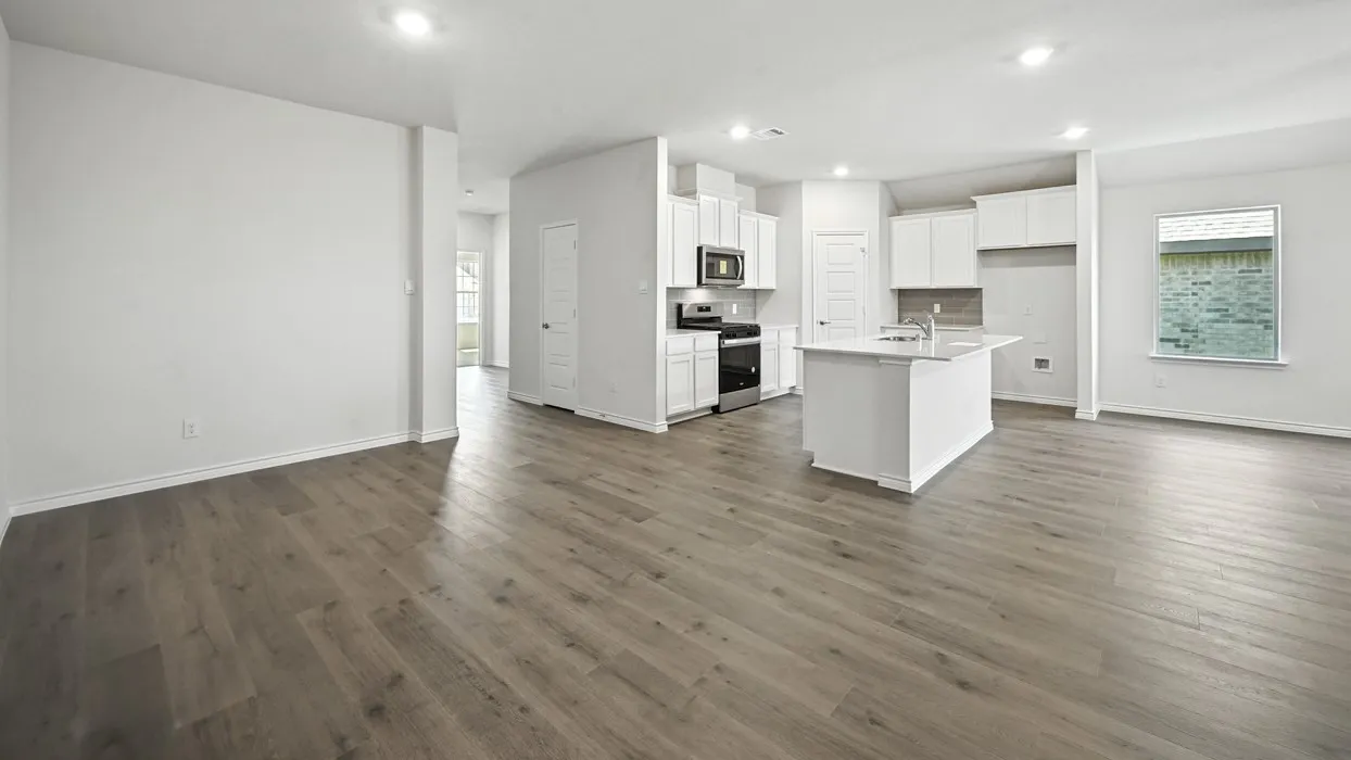 Wood-finish flooring throughout, recessed lighting, white kitchen cabinetry, stainless steel appliances, and a central island with a sink