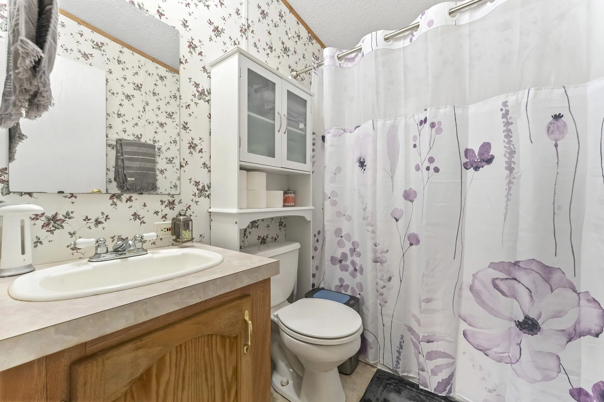 Vanity with integrated sink, wood-finish cabinetry, and neutral countertop