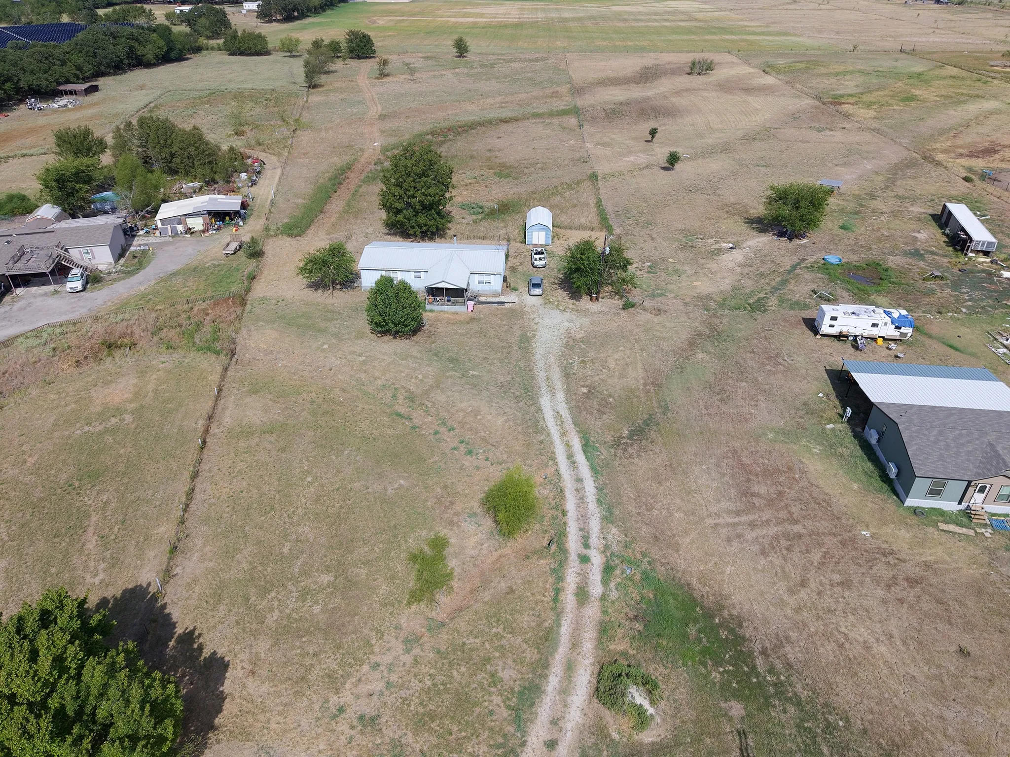 Expansive property featuring a central residence, outbuilding, and mature trees on a level lot