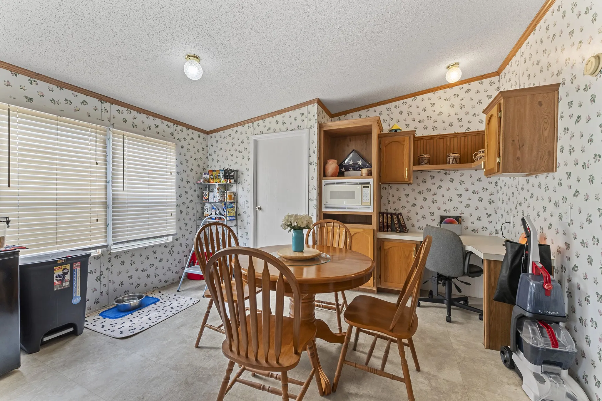 Built-in wood cabinetry with a dedicated desk area, multiple windows with blinds, and overhead lighting fixtures