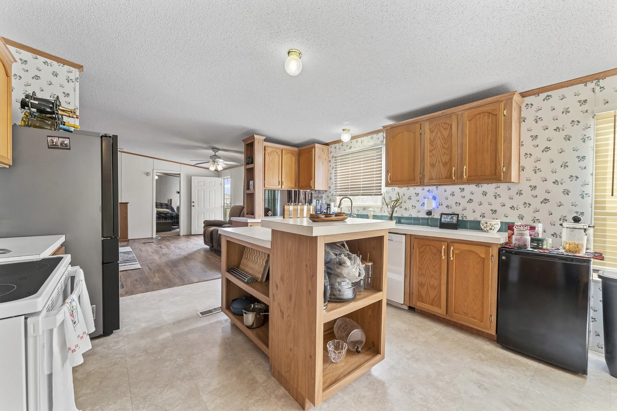 Kitchen featuring wood cabinetry, solid surface countertops, and an open island with shelving
