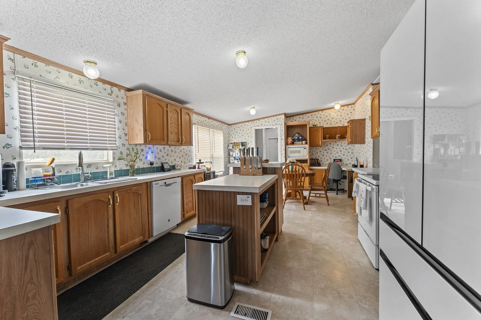 Kitchen featuring wood cabinetry, a central island, and white appliances