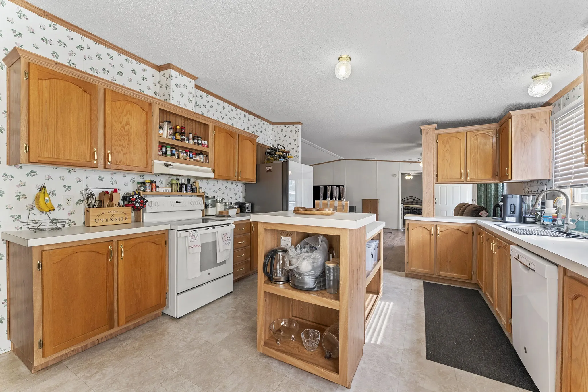 Kitchen featuring wood-finish cabinetry, white countertops, a white electric range, and a white dishwasher
