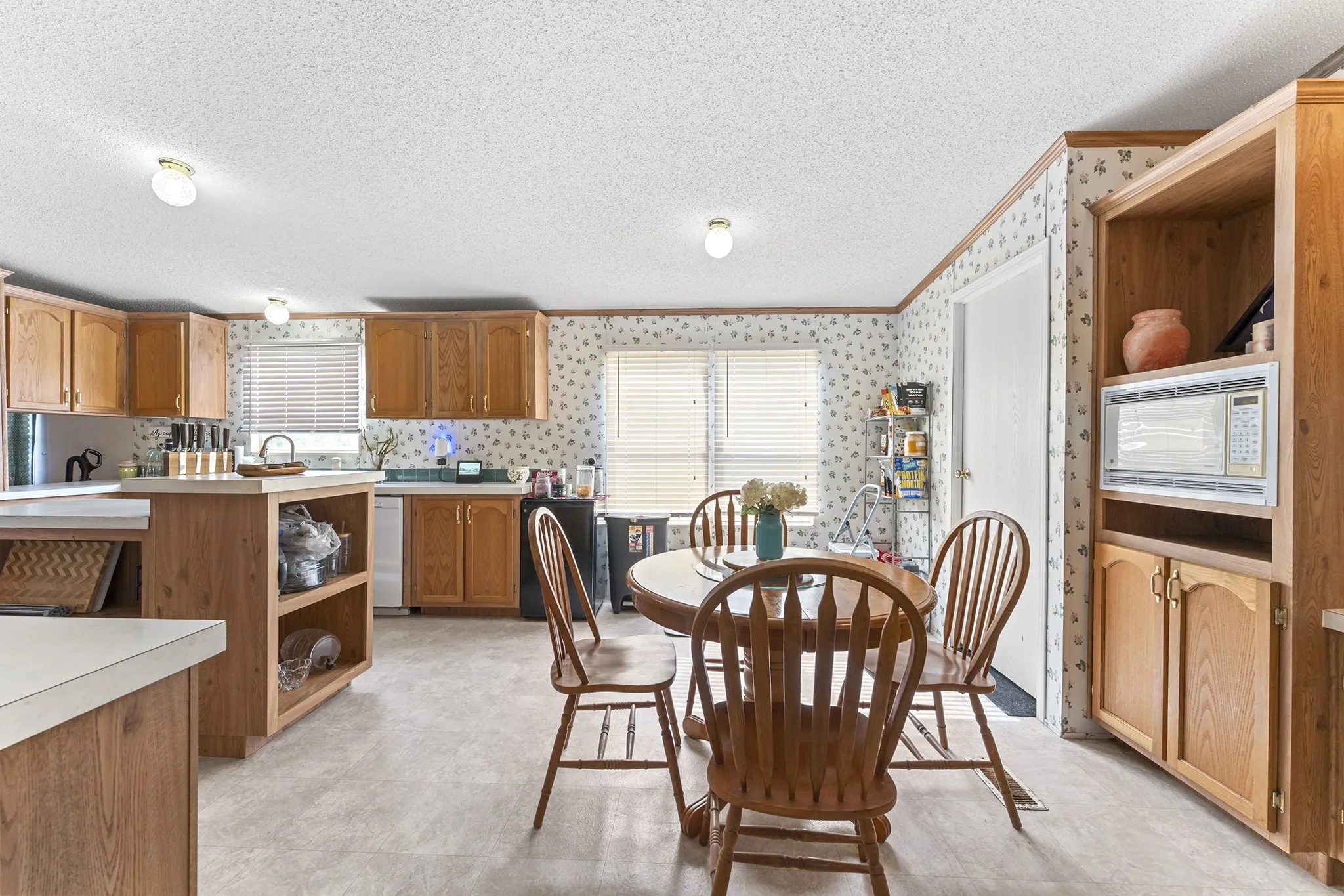 Kitchen featuring wood-finish cabinetry, built-in microwave, and a dining area with a round table