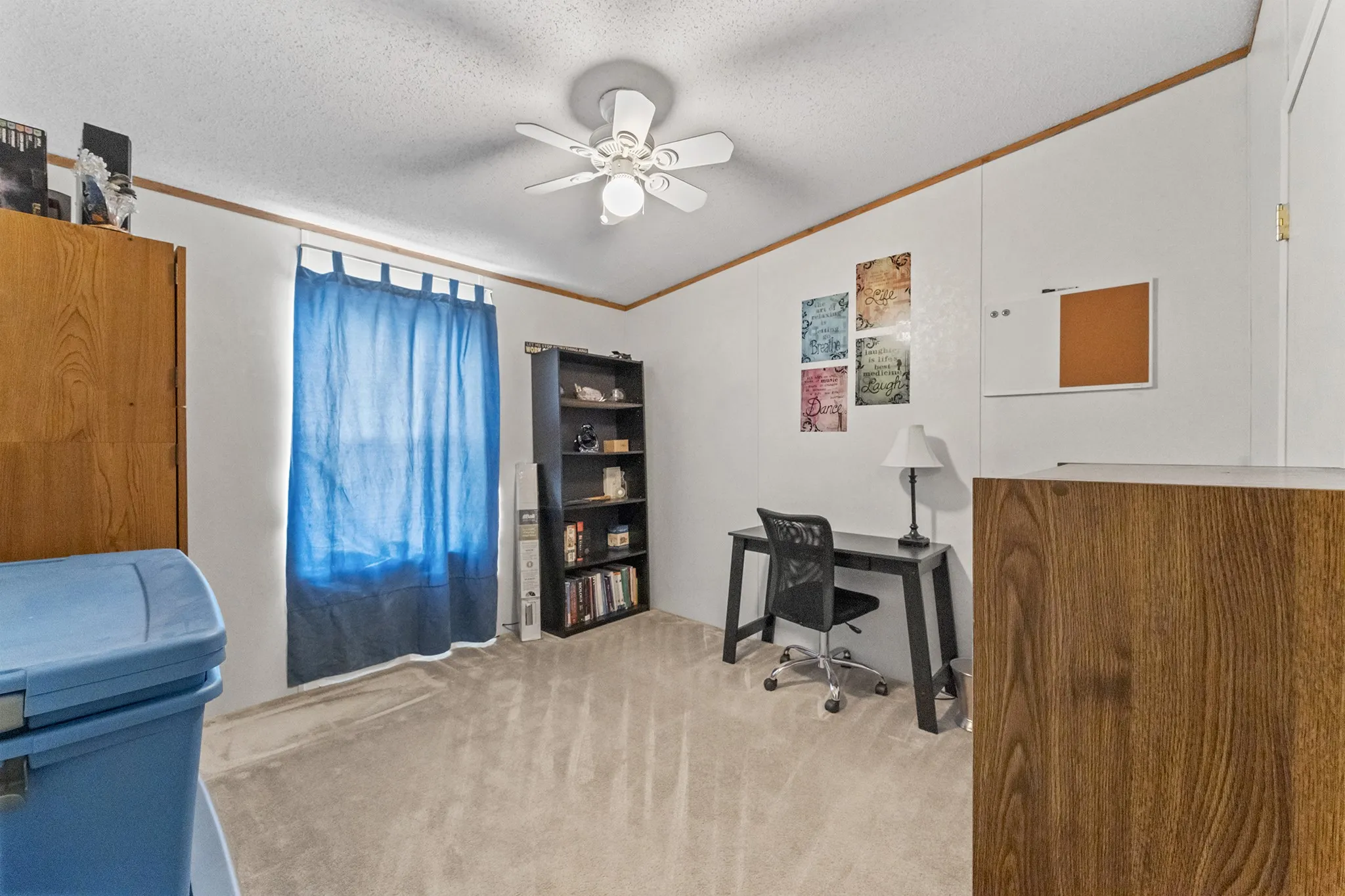 White walls with wood-finish trim, textured ceiling, and light-colored carpeting
