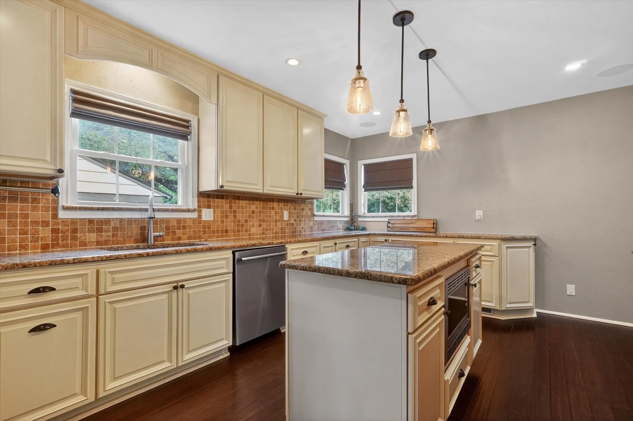 Kitchen featuring a center island, pendant lighting, stone countertops, integrated microwave, and wood-finish flooring