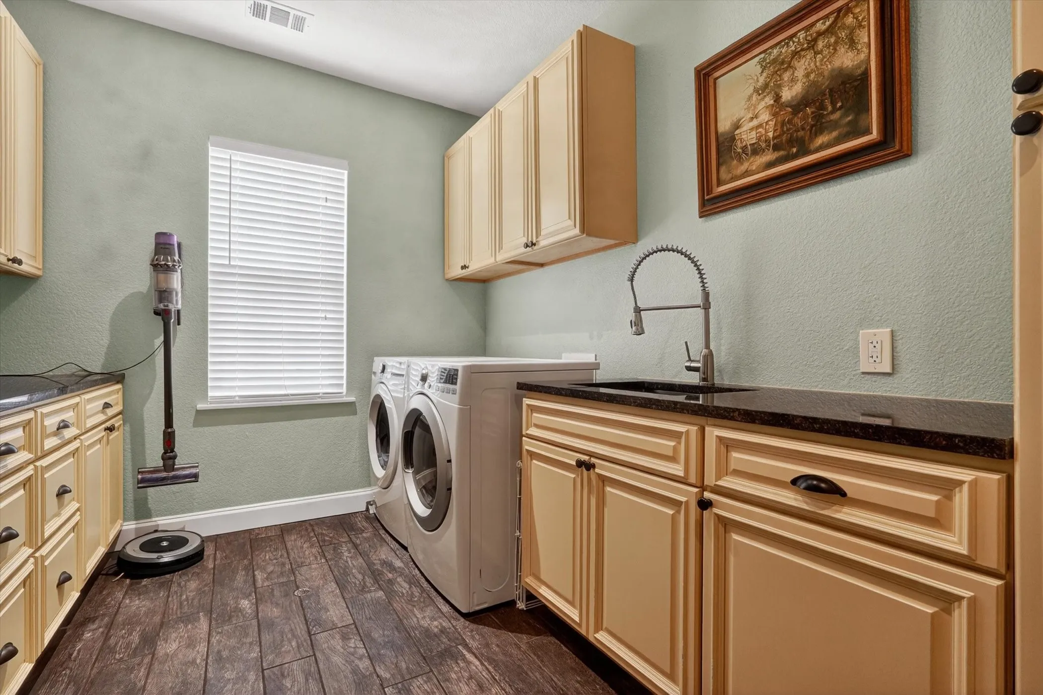 Laundry room featuring wood-finish flooring, built-in cabinetry, a utility sink with a gooseneck faucet, and countertop space