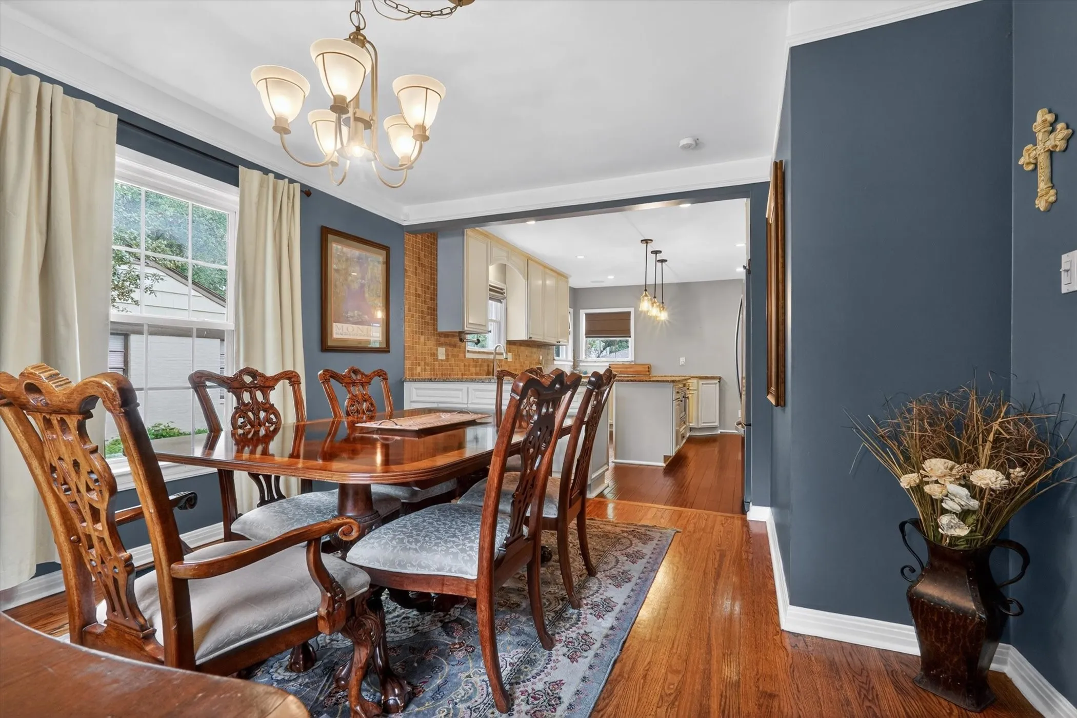 Dining area featuring hardwood flooring, a chandelier with frosted glass shades, and a cased opening to the kitchen