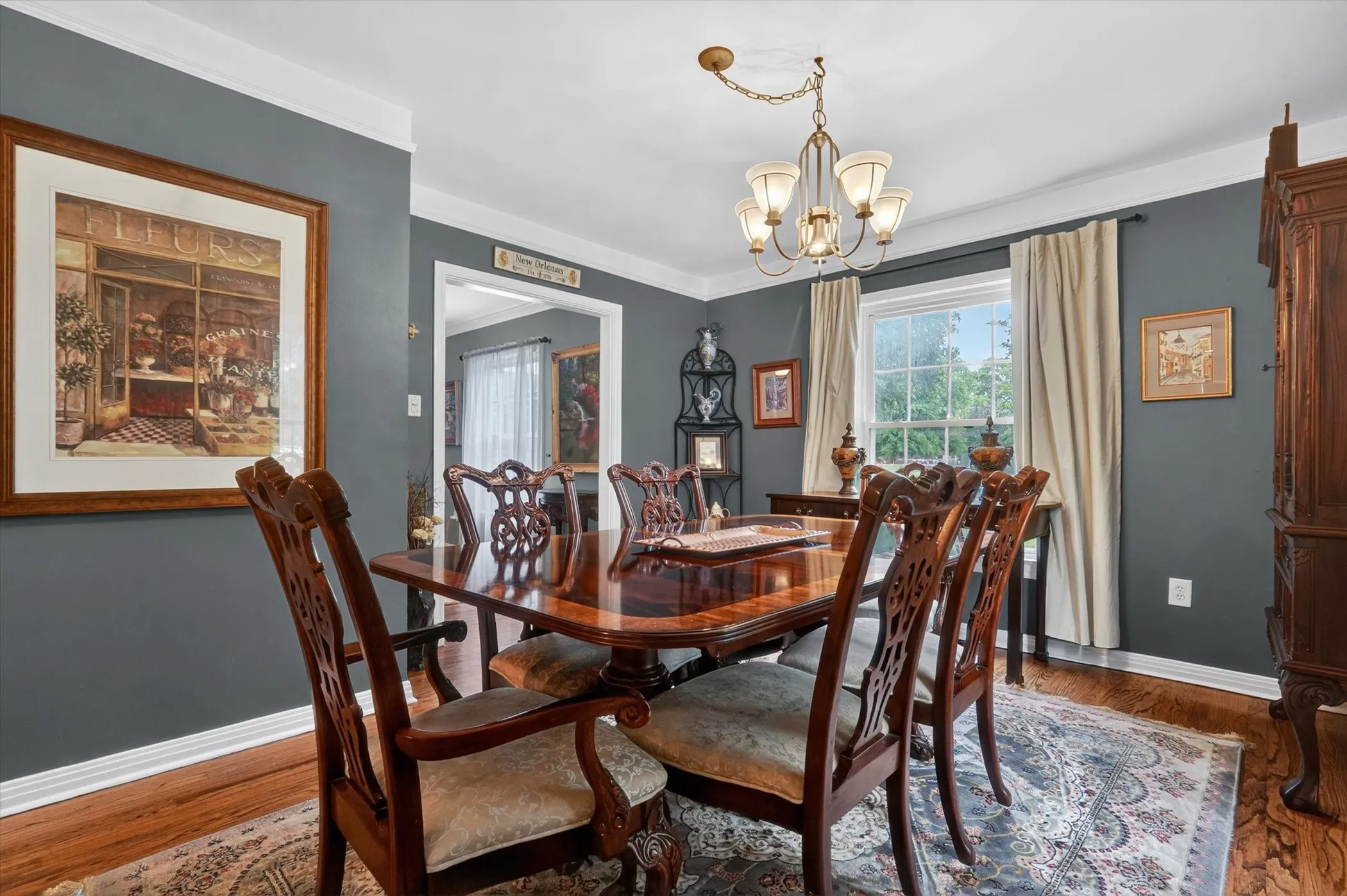 Dining area featuring wood-finish flooring, dark-painted walls, white trim, and a brass-tone chandelier