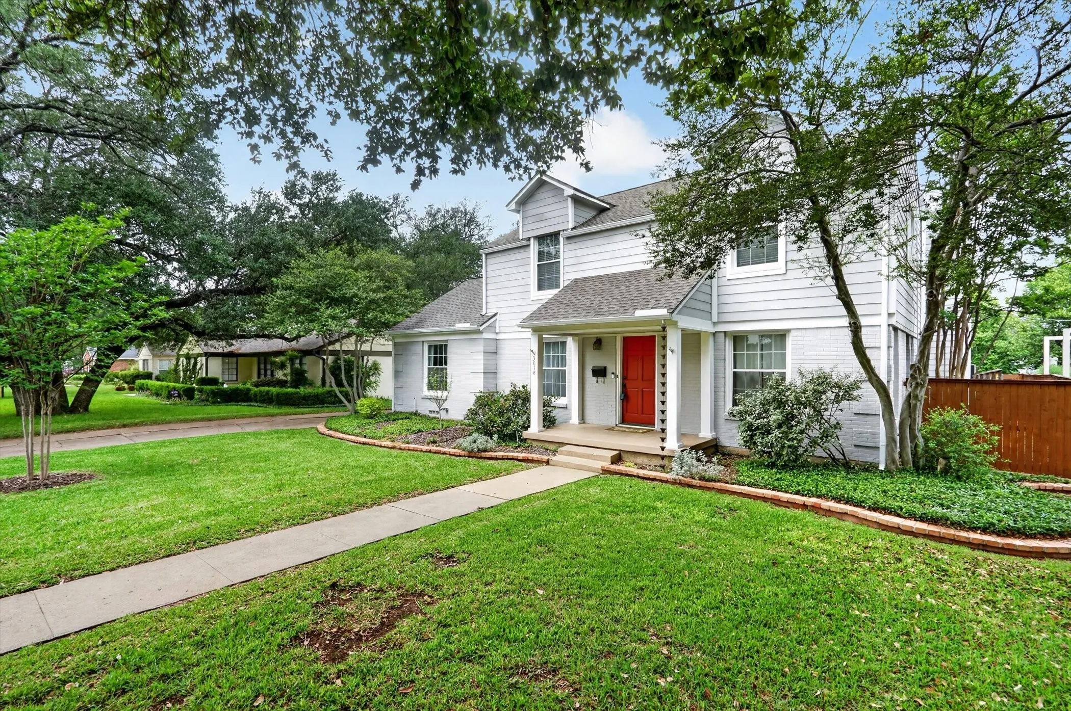 Two-story residence featuring light gray siding and a contrasting red front door