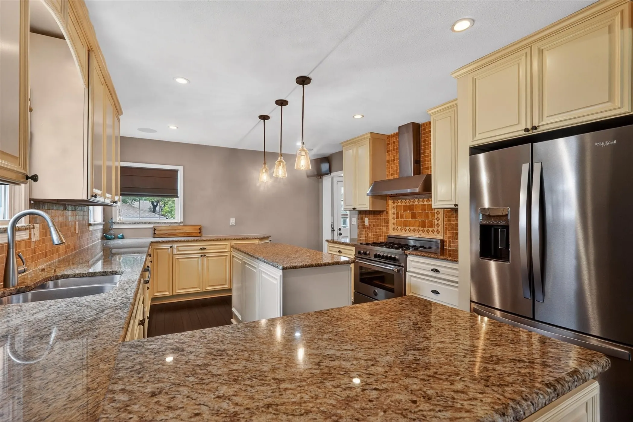 Kitchen featuring extensive granite countertops, stainless steel appliances, a gas range with a decorative tile backsplash, pendant lighting, and recessed ceiling lights