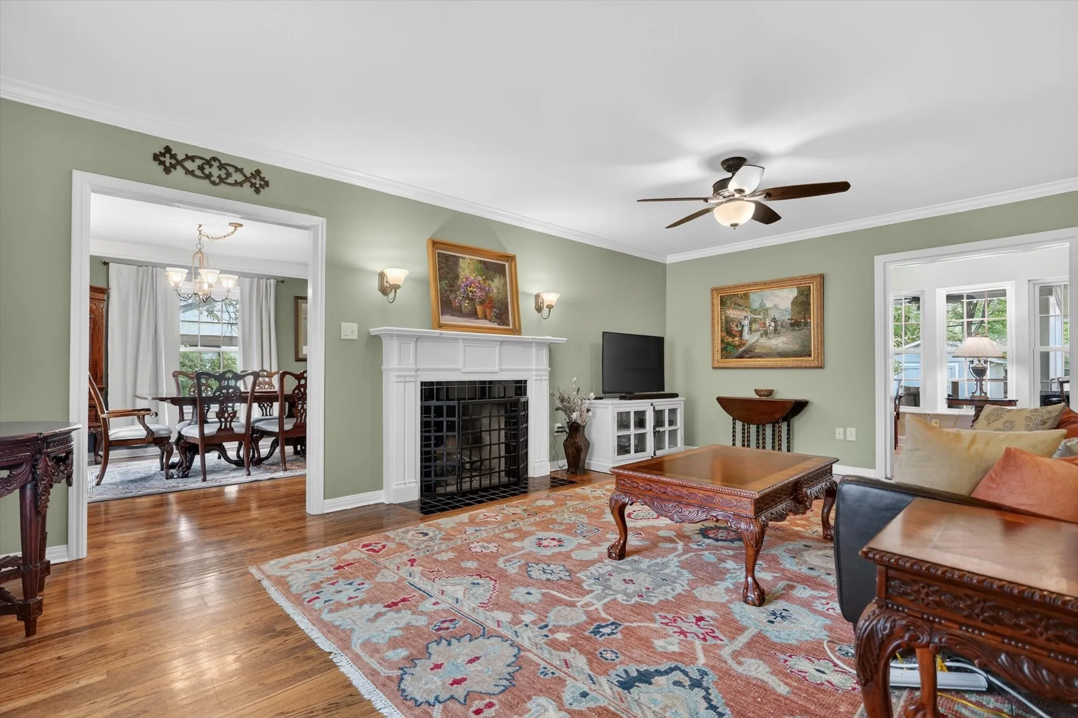Hardwood flooring throughout, crown molding, and a fireplace with a white mantel and black grate