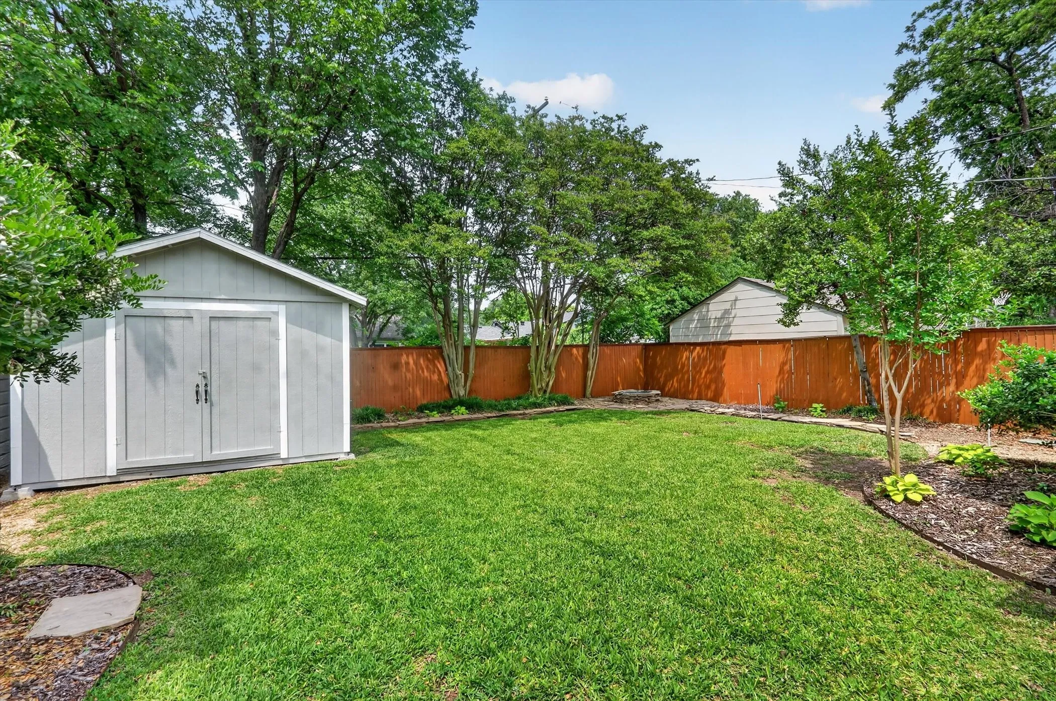Expansive backyard featuring a manicured lawn, a detached storage shed, and a privacy fence