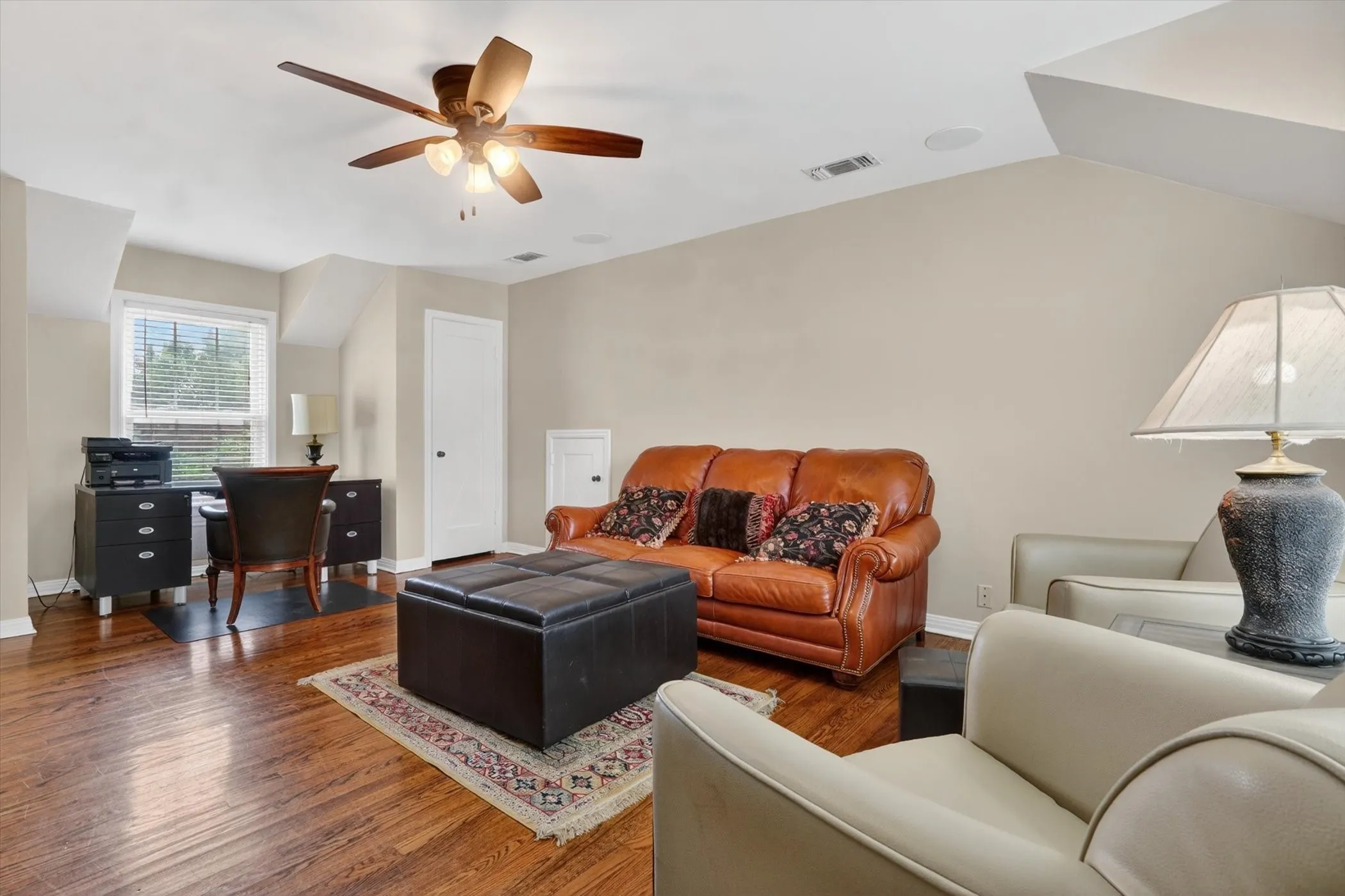 Hardwood flooring throughout a versatile room with a sloped ceiling and recessed lighting