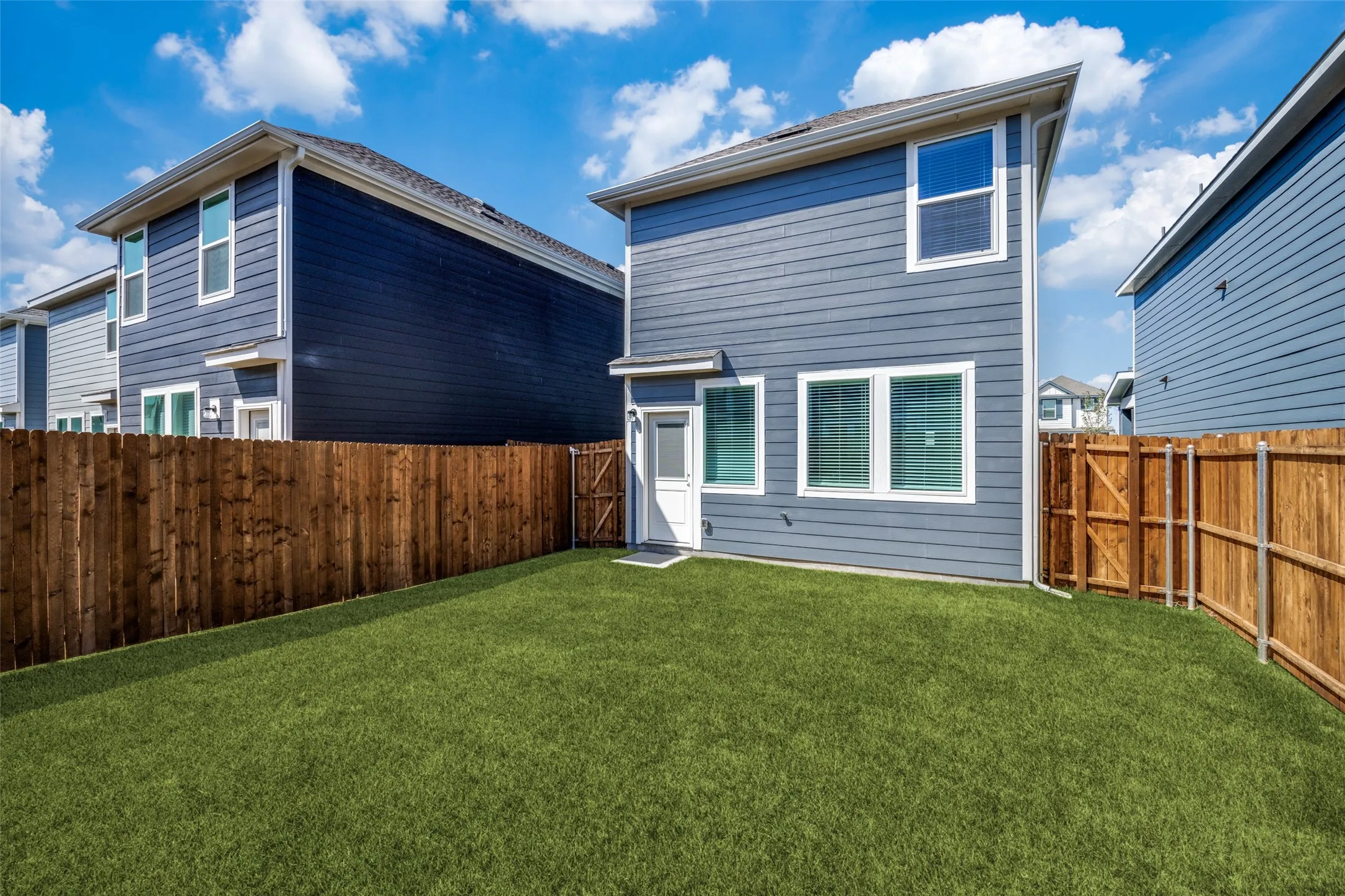 Fenced backyard featuring an artificial turf lawn