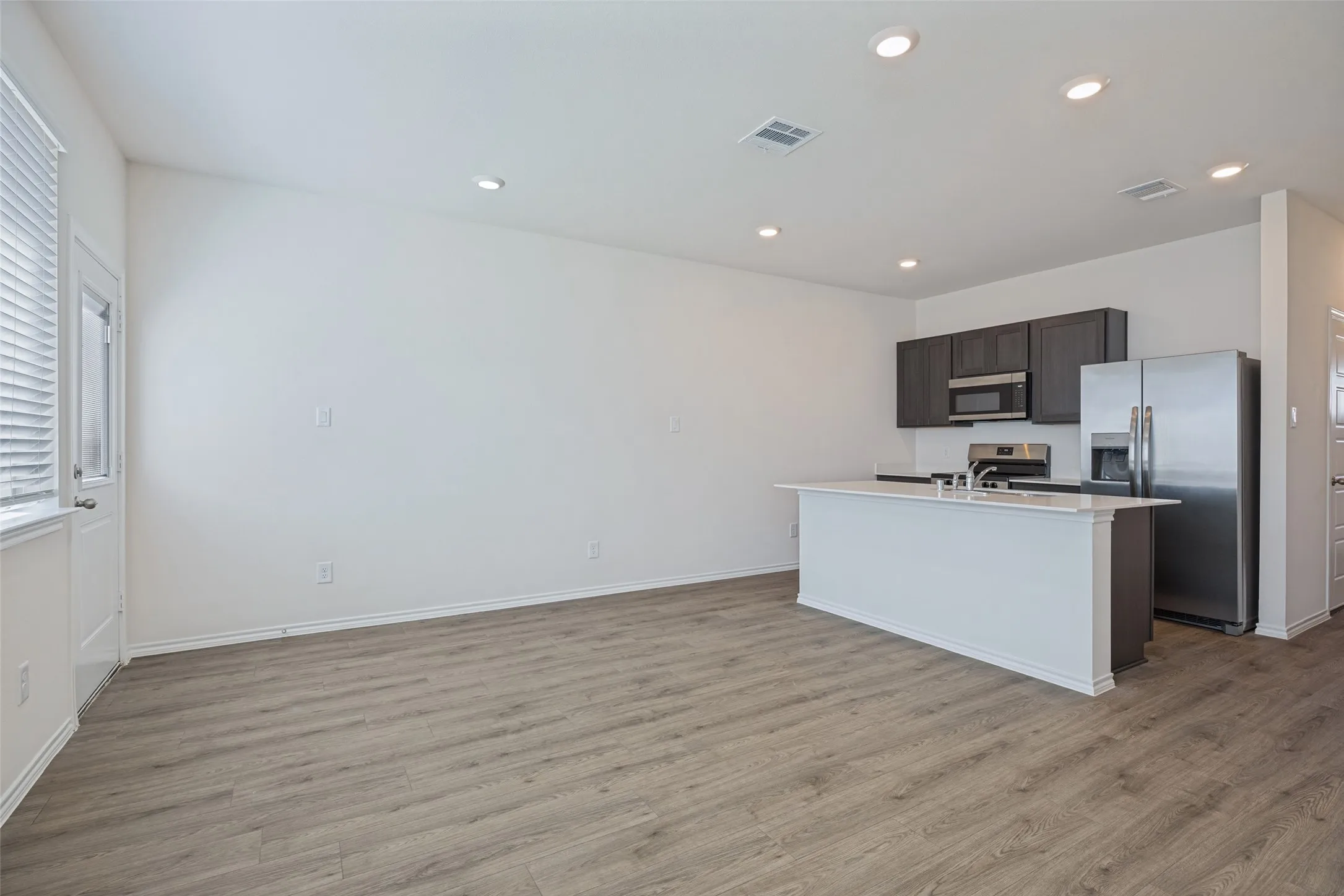Contemporary kitchen with dark cabinetry, stainless steel appliances, and a central island with a sink