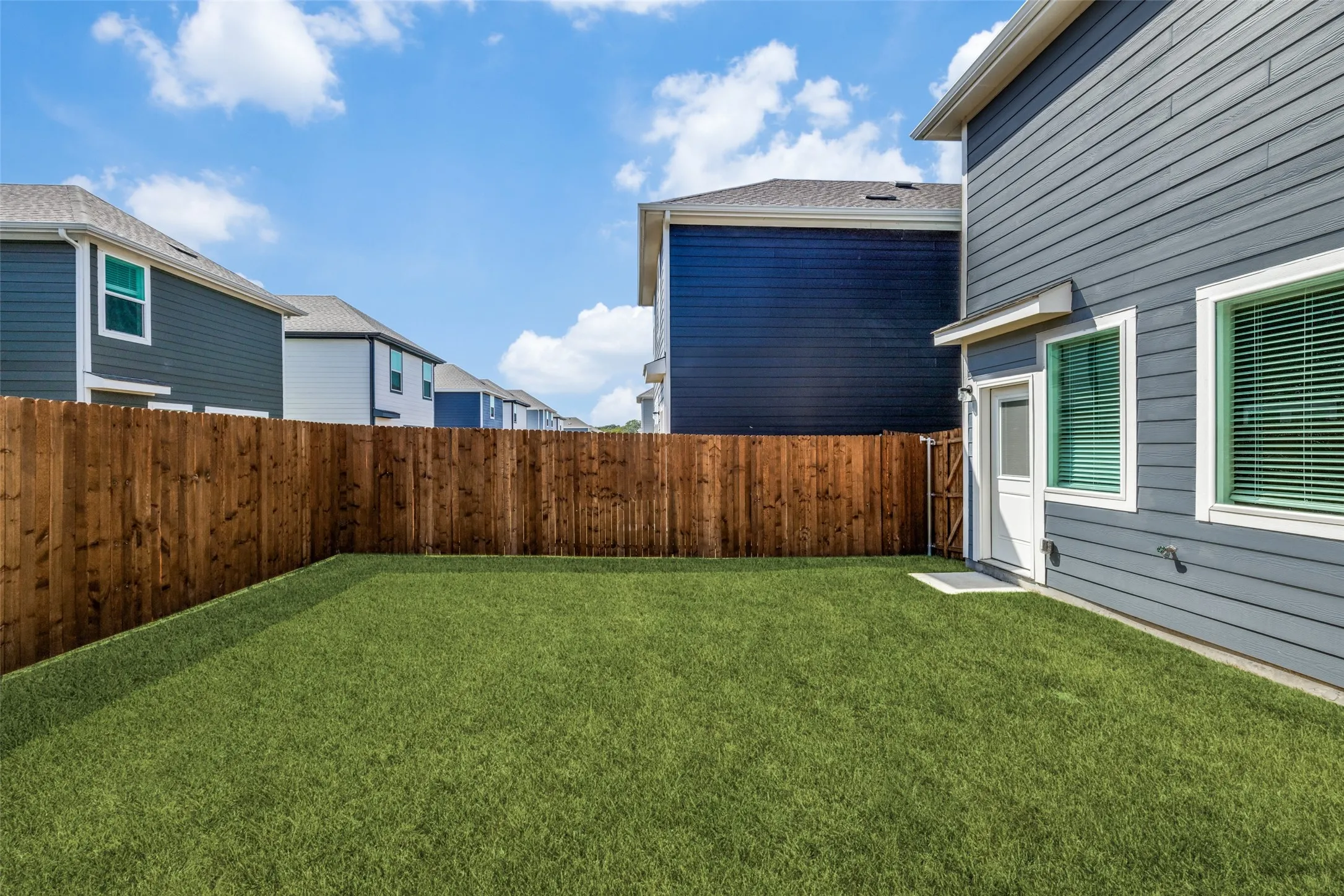 Private fenced backyard featuring a level lawn and wood privacy fence