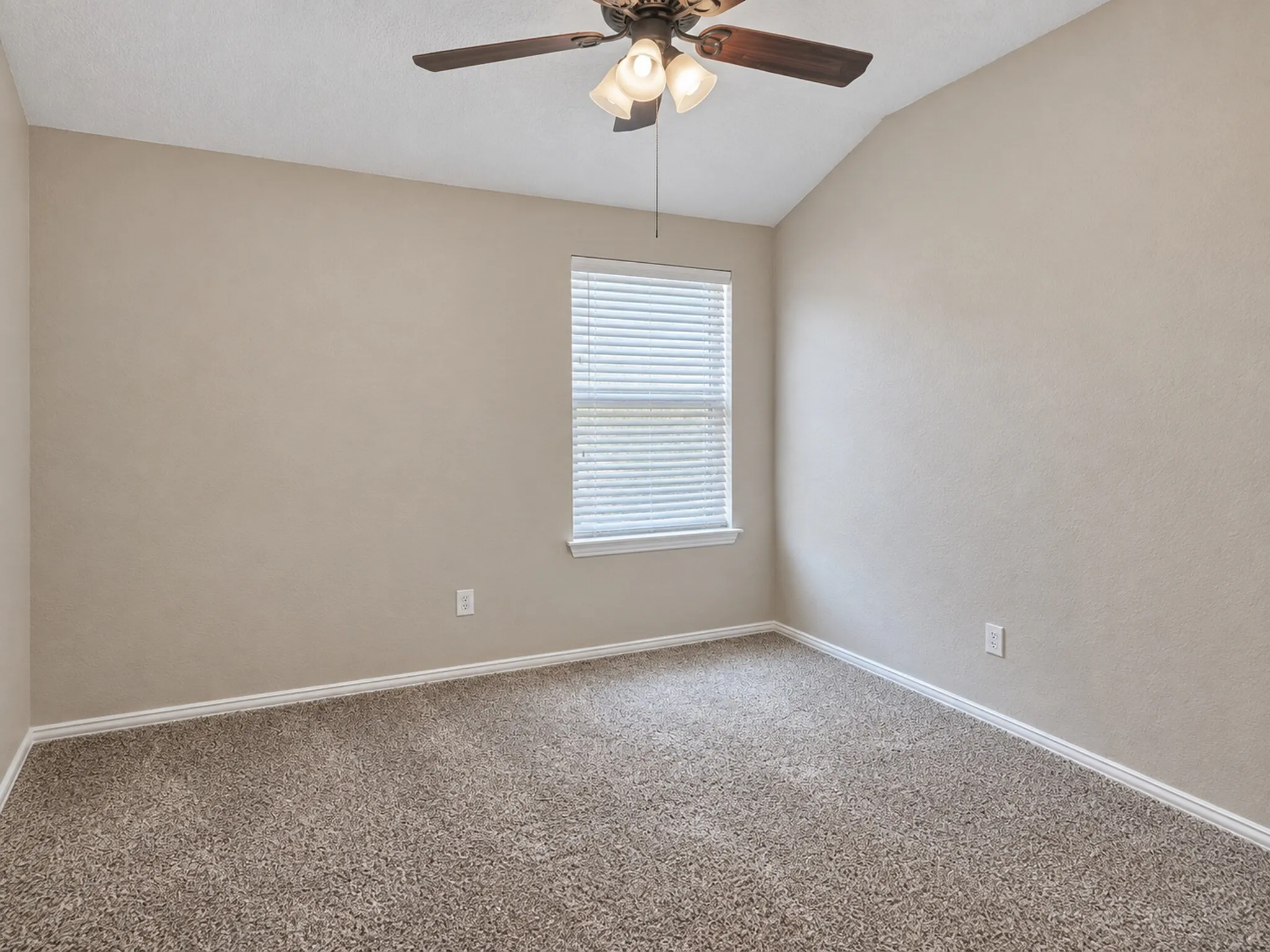 Vaulted ceiling with a ceiling fan, window with blinds, and textured walls