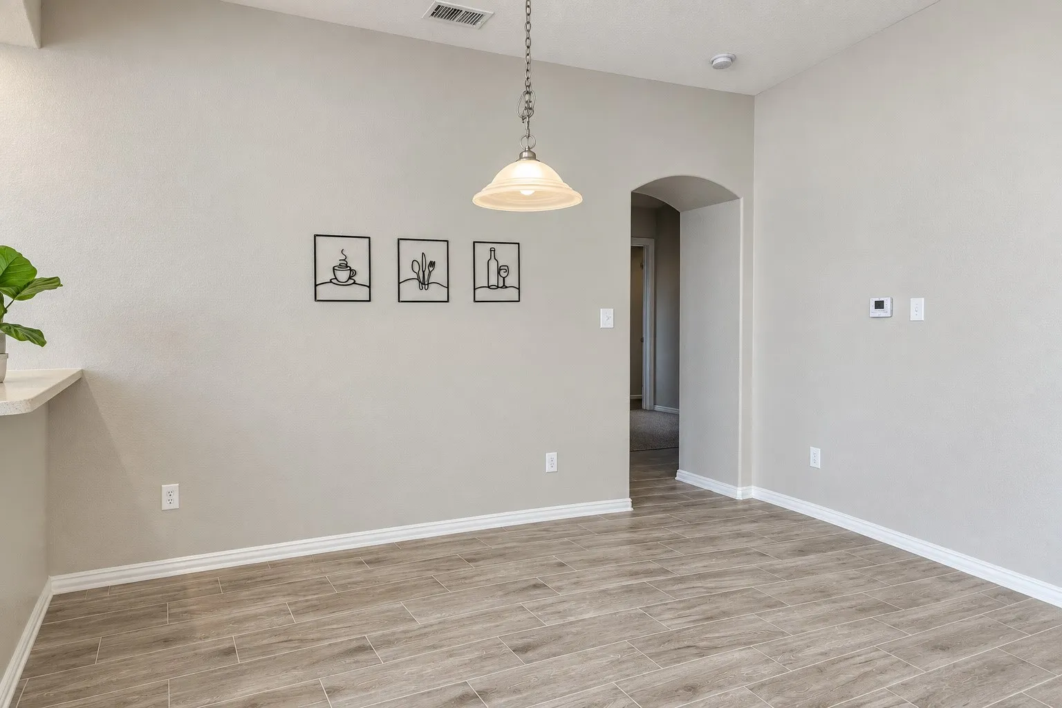 Vaulted ceiling with a pendant light fixture, arched doorway, and wood-finish tile flooring