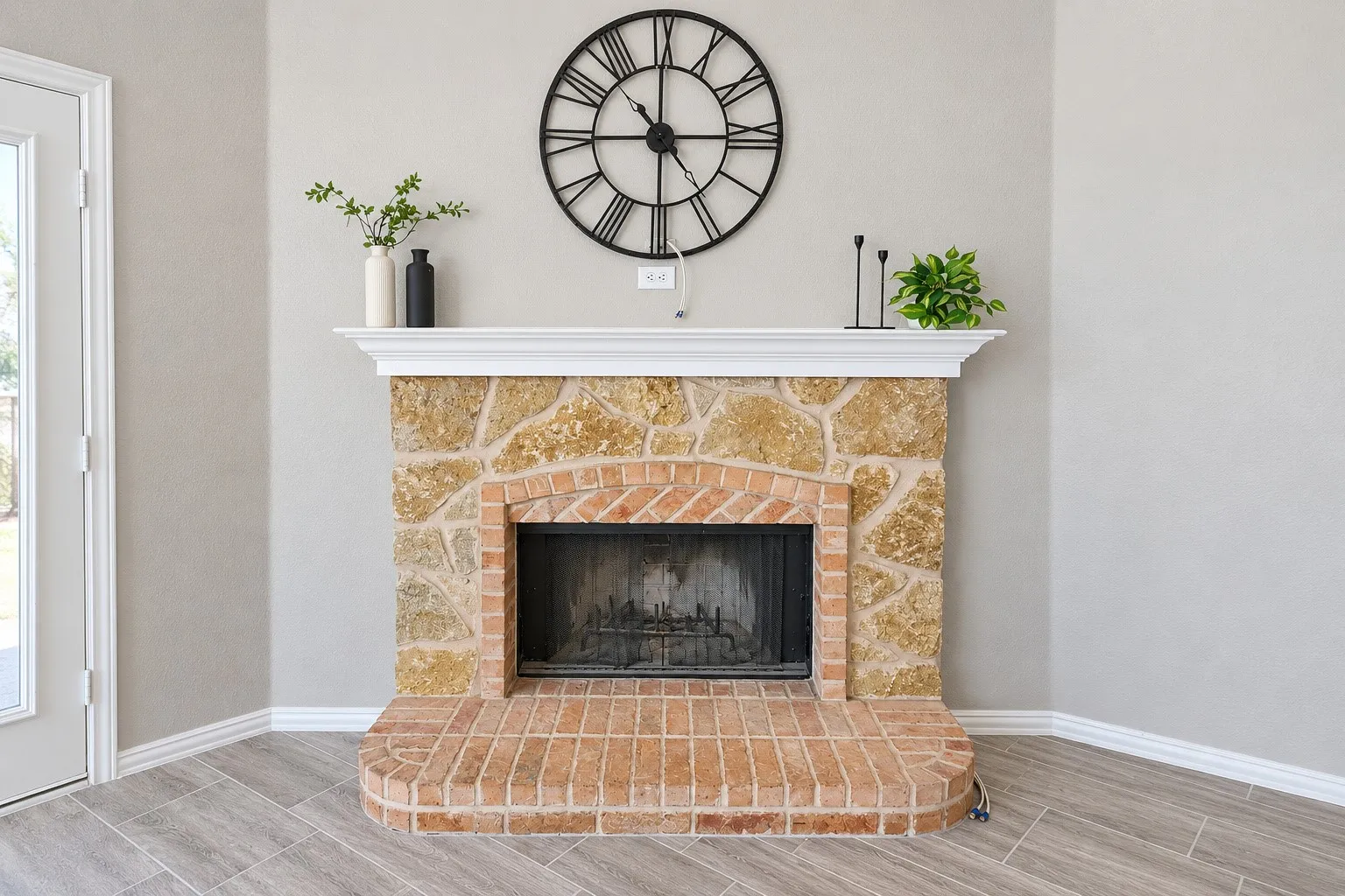 Stone and brick fireplace with a white mantel, hearth, and wood-finish flooring