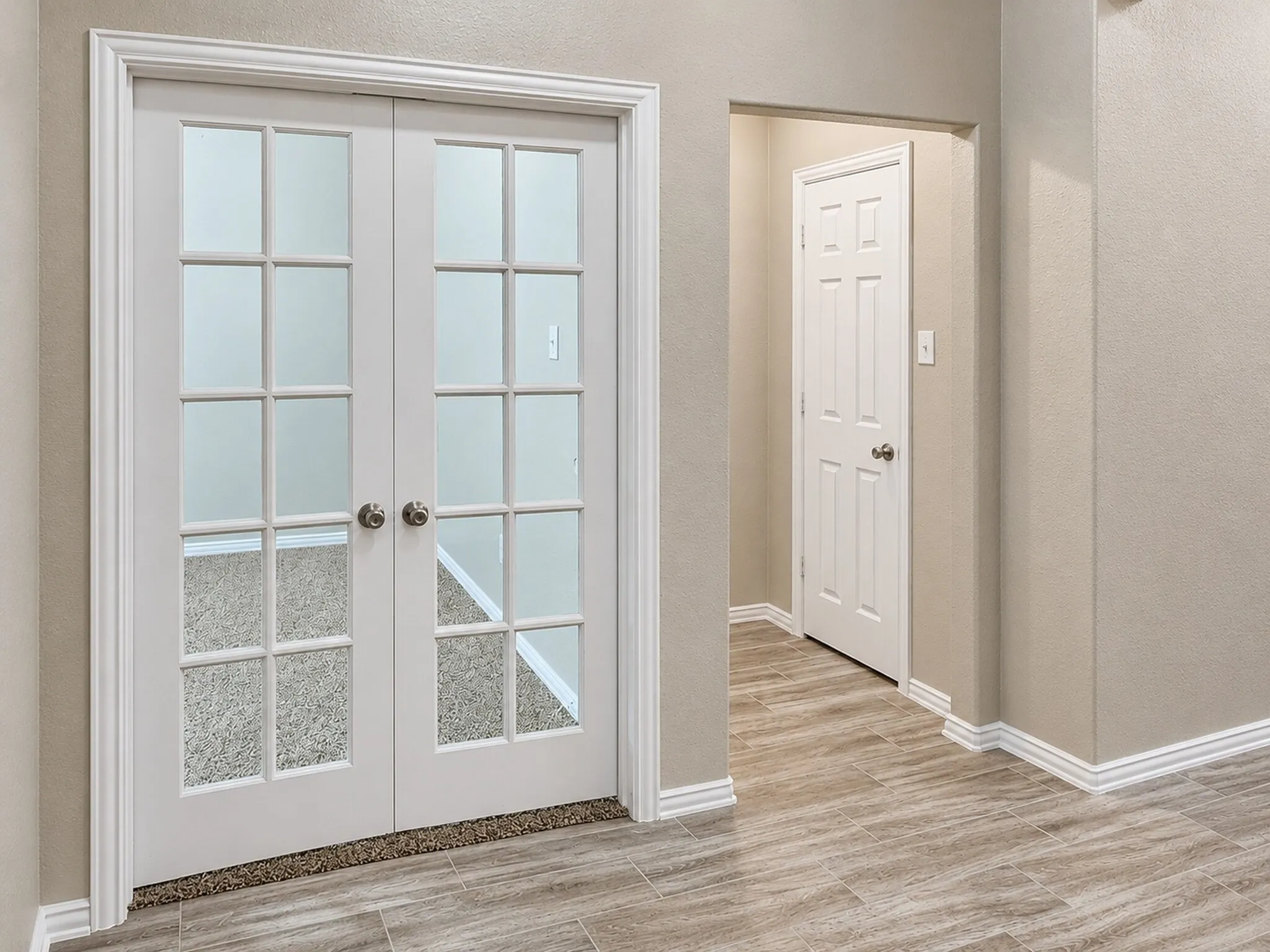 French doors with paneled glass, wood-finish flooring, white trim, and neutral wall tones