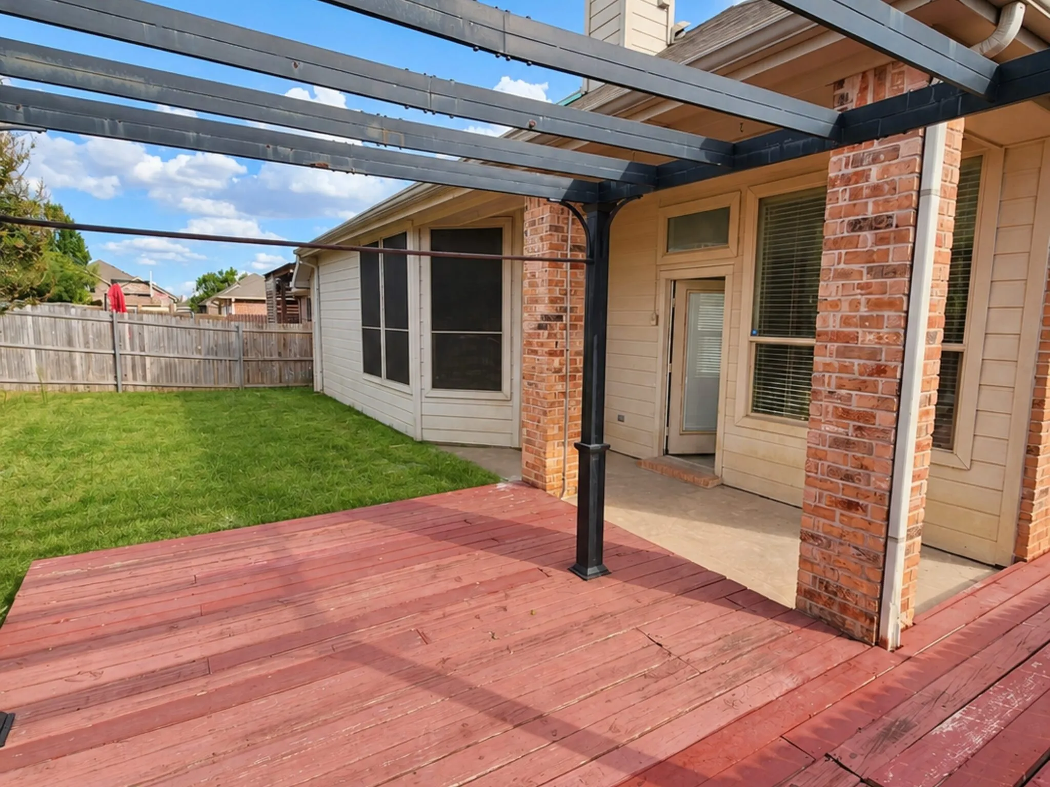 Spacious wooden deck with an attached pergola, leading to a manicured lawn