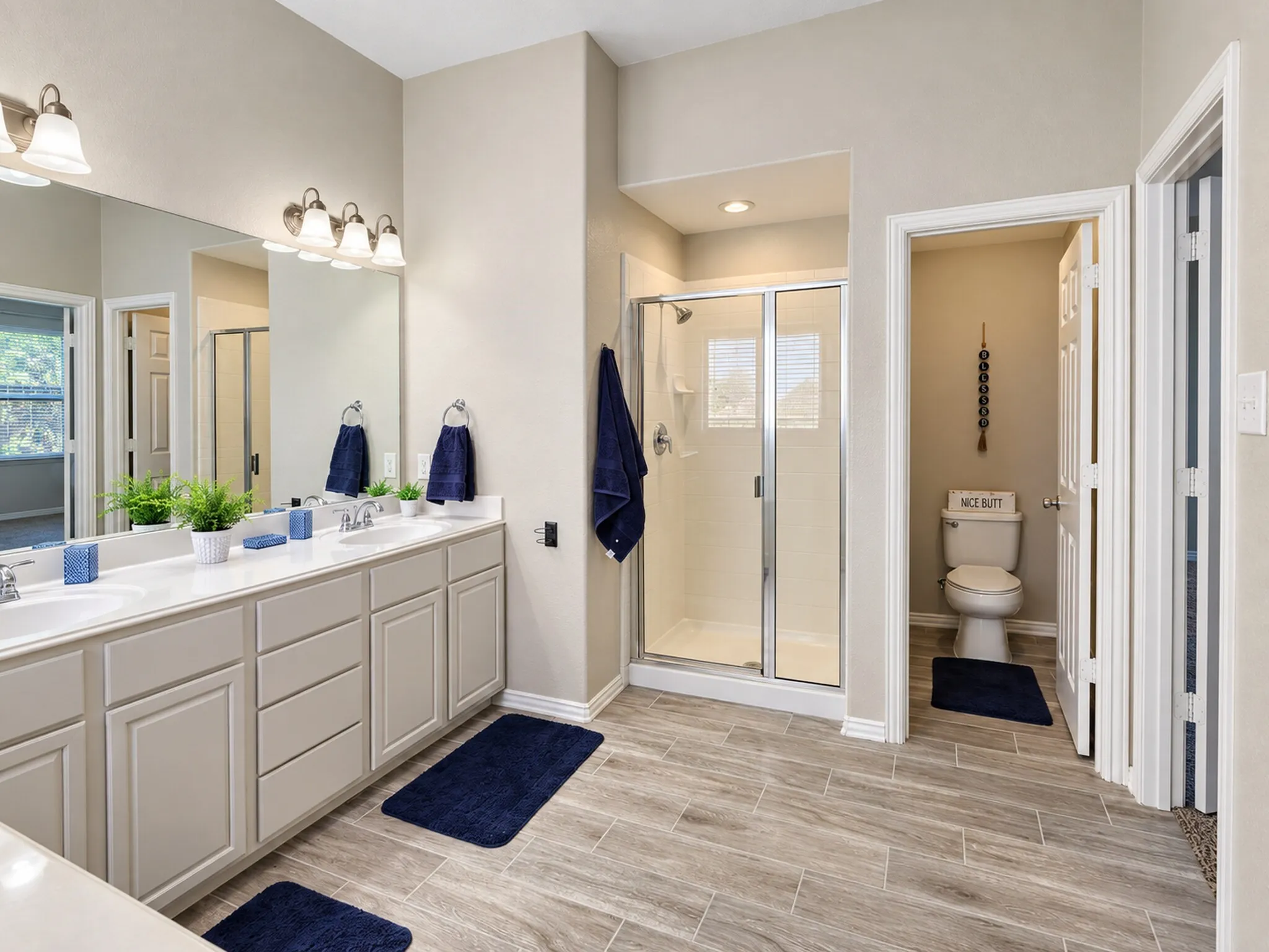 Dual vanity with integrated sinks, wood-finish flooring, glass-enclosed shower, built-in cabinetry, and recessed lighting