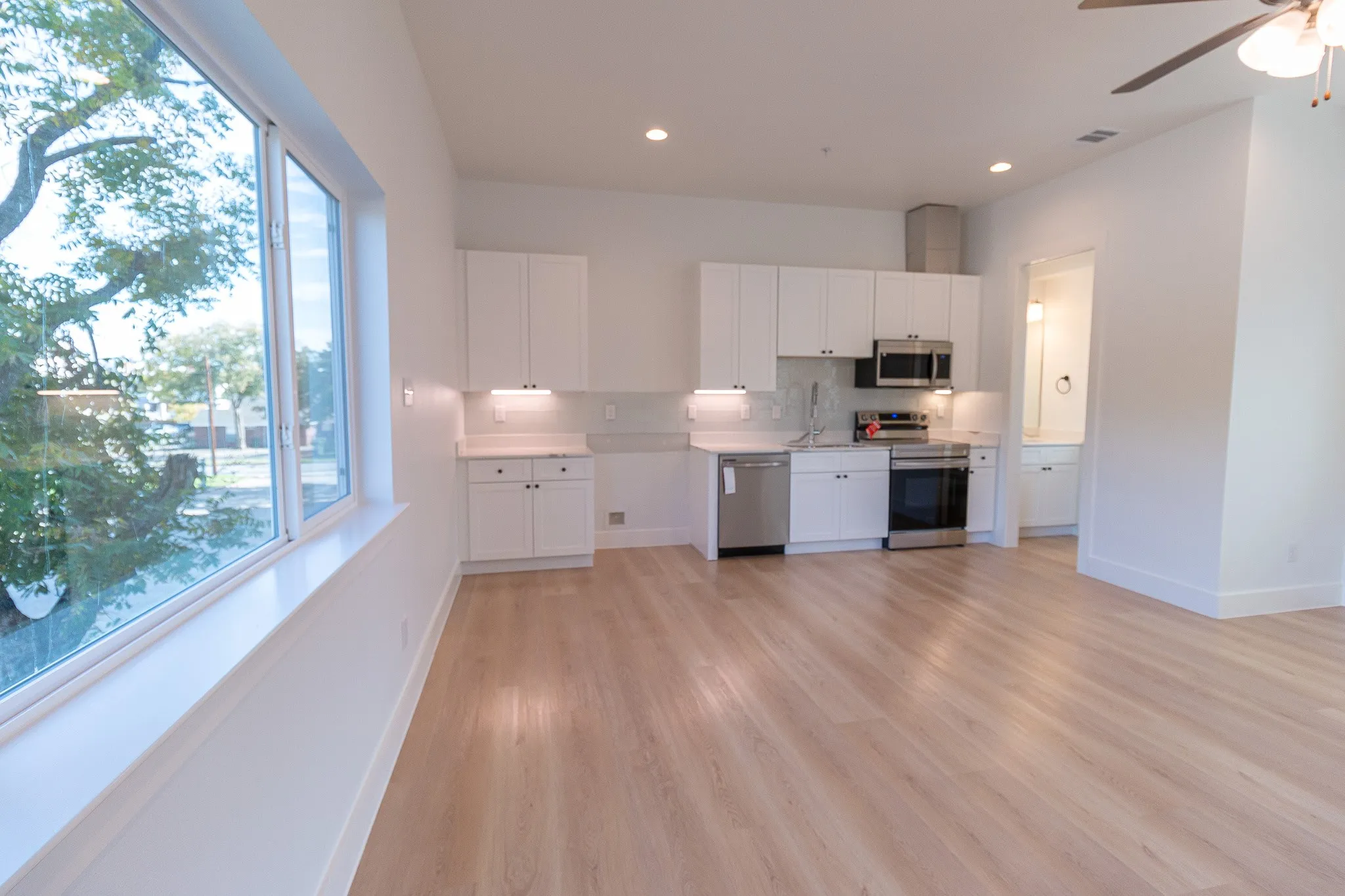 Kitchen with a healthy amount of sunlight, white cabinets, stainless steel appliances, and light hardwood / wood-style floors