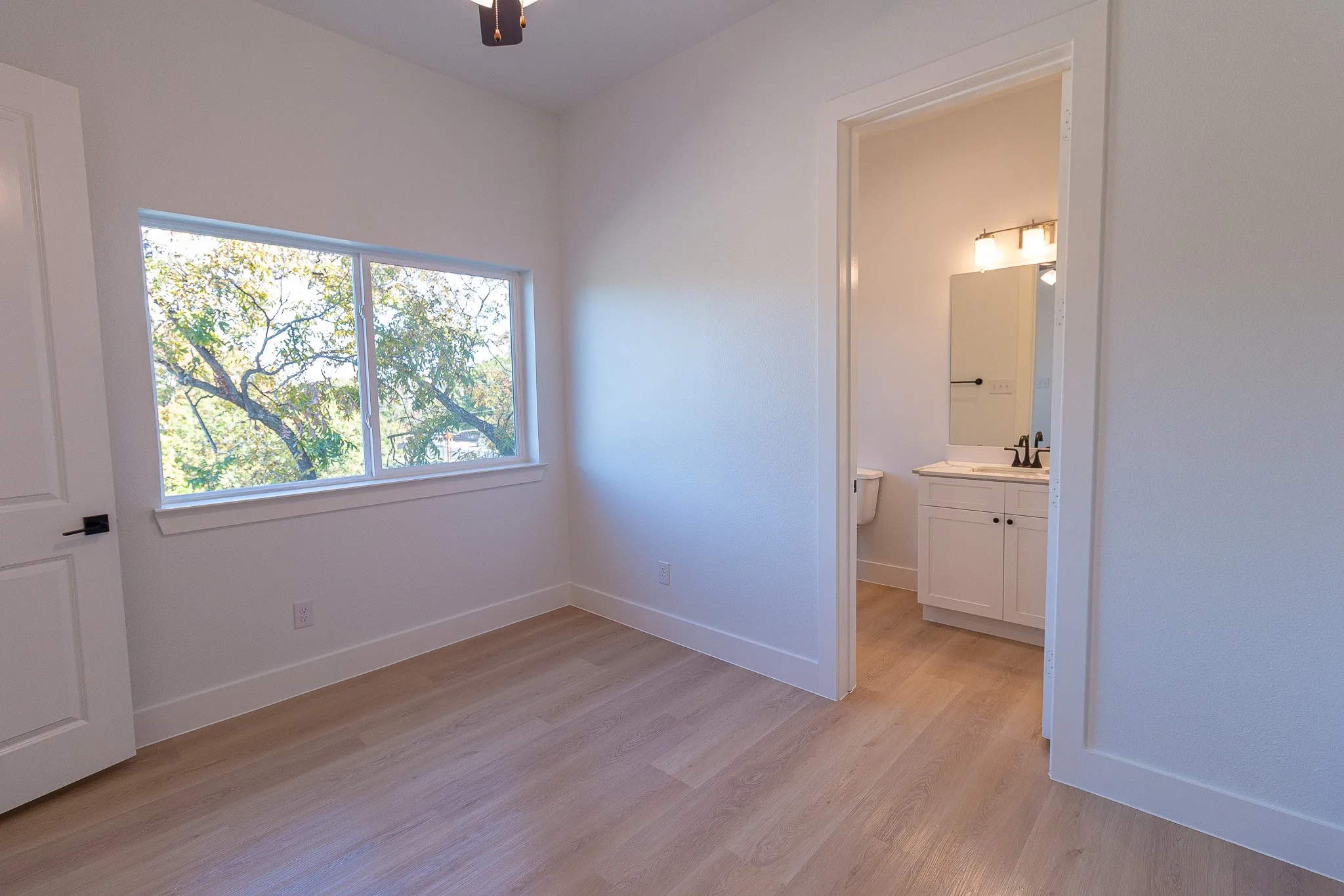 Unfurnished bedroom with light wood-type flooring, ensuite bath, ceiling fan, and sink