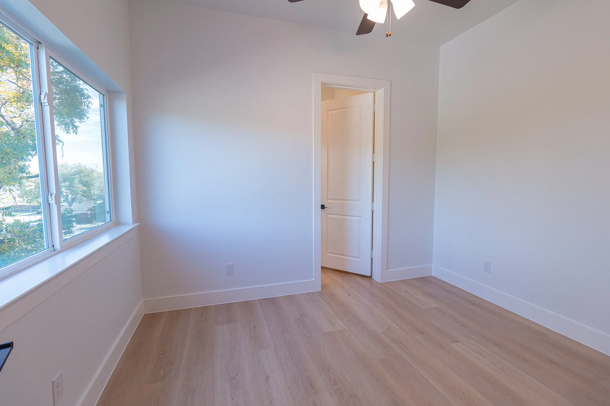 Spare room with ceiling fan, plenty of natural light, and light hardwood / wood-style flooring