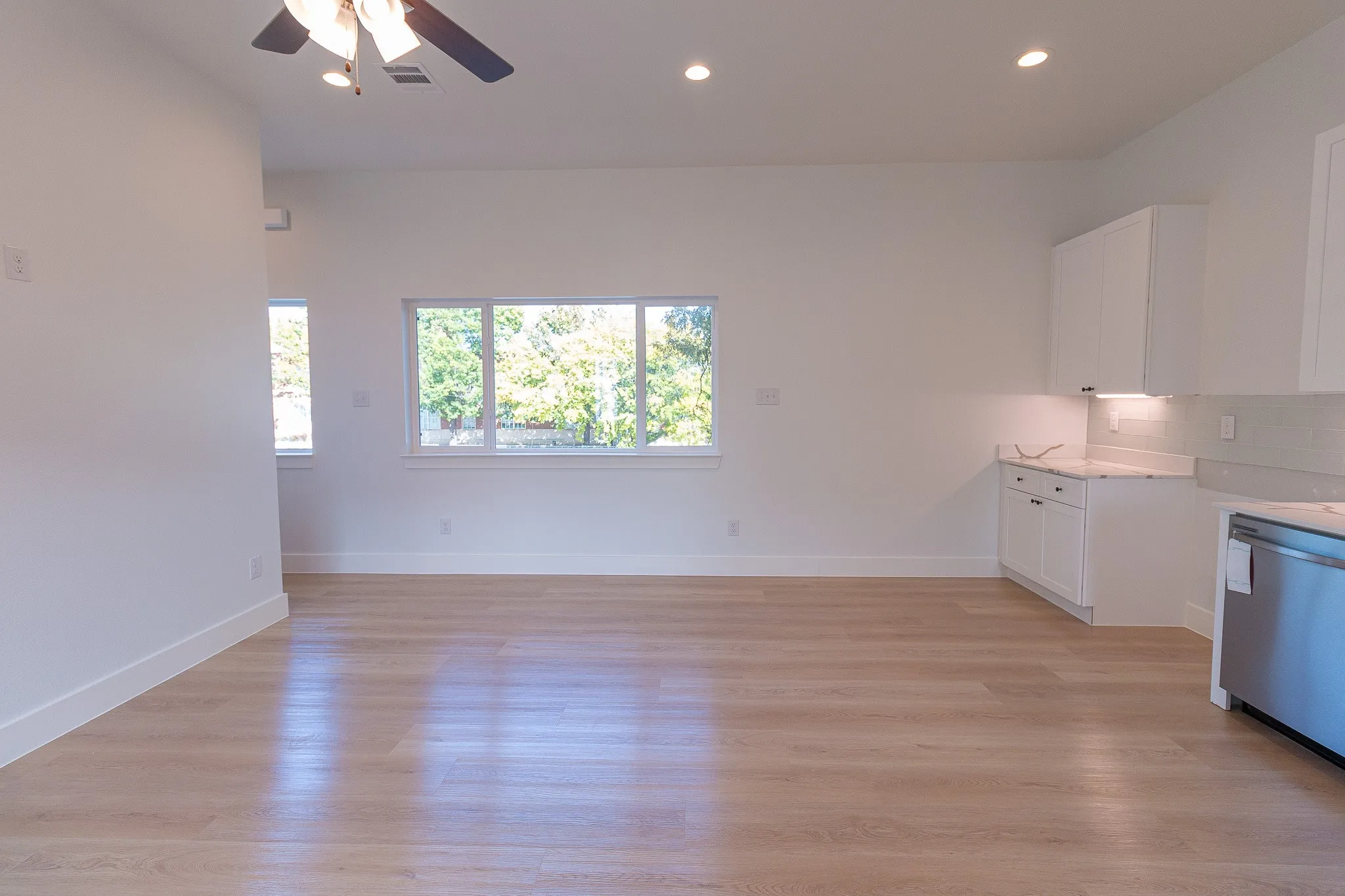 Kitchen featuring white cabinets, light hardwood / wood-style floors, light stone counters, and ceiling fan