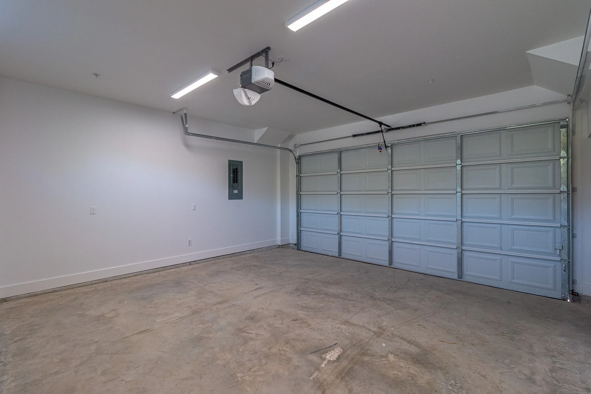 Garage featuring electric panel and a garage door opener