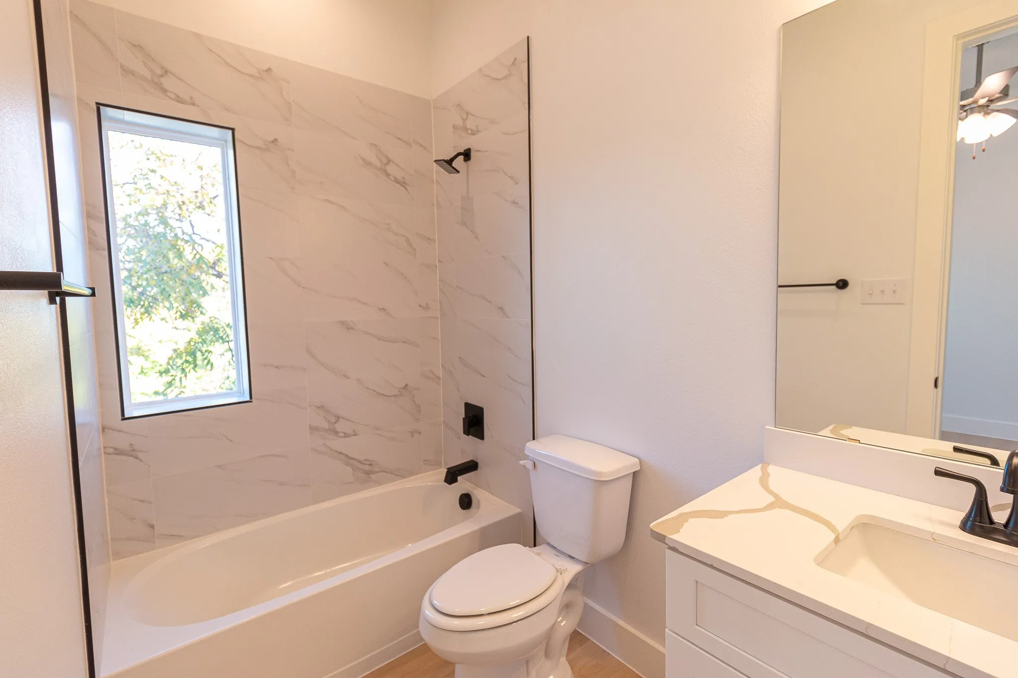 Full bathroom with a wealth of natural light, toilet, vanity, and tiled shower / bath